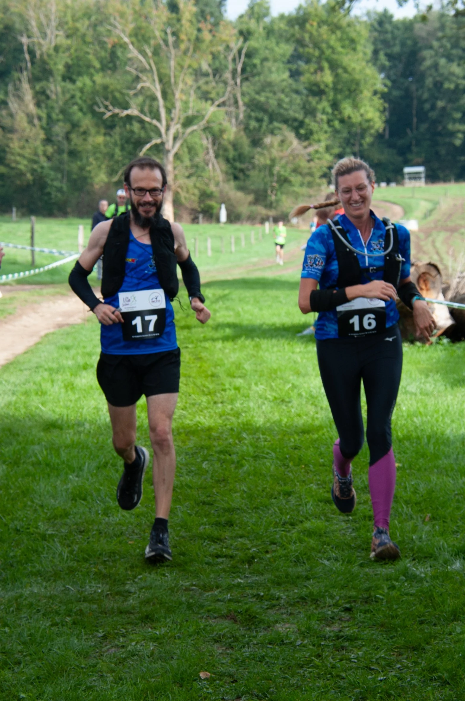 Deux coureurs participant à une course dans un parc vert.