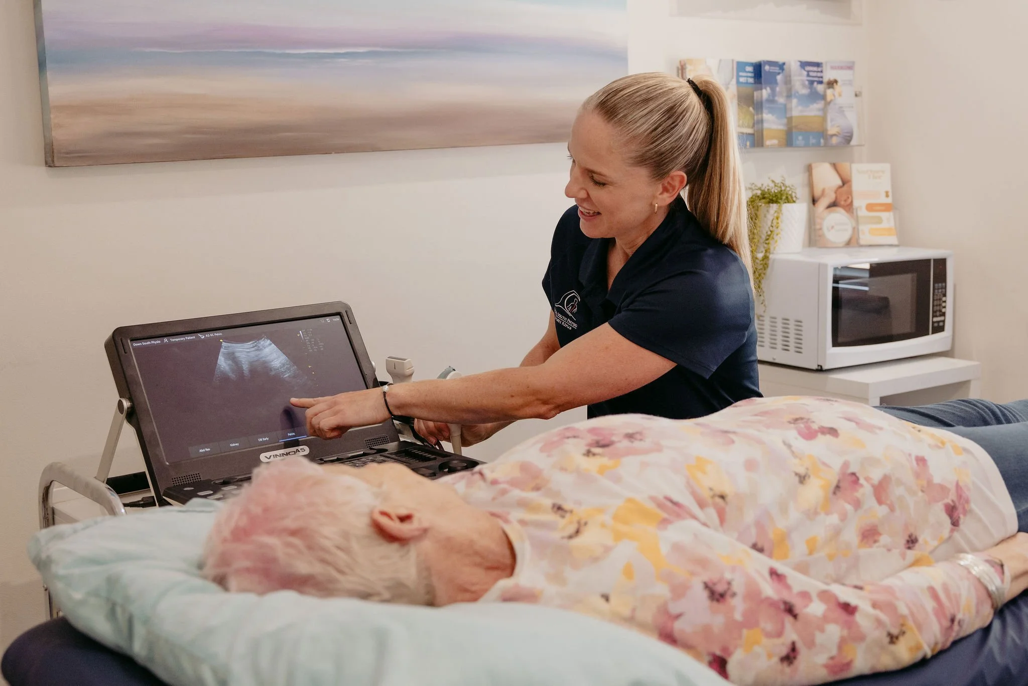 A veterinarian shows a digital ultrasound of a pregnant animal on a screen to a patient in a veterinary clinic.
