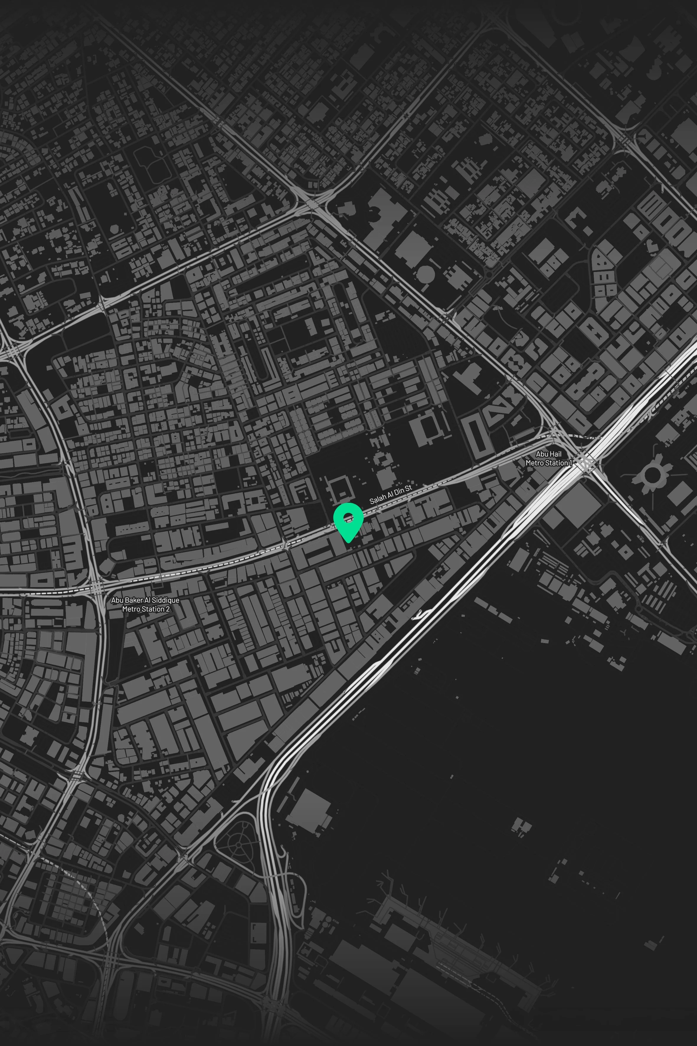 A digital map of a city at night with roads and highways highlighted in white against a dark background. A location marker is centered on one area of the map.