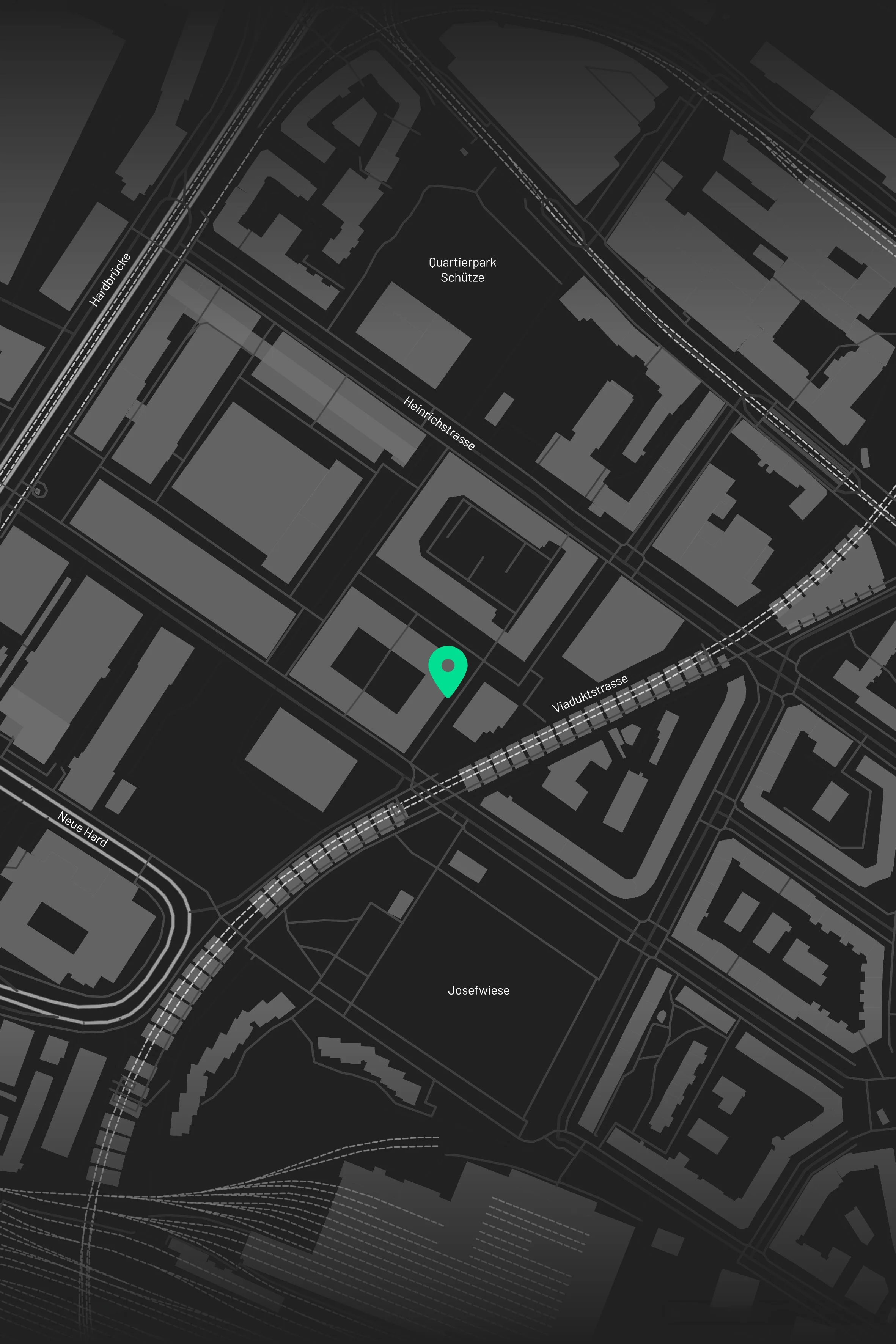 Nighttime map of a city with light-colored roads and rail lines on a dark background, with a green location marker at the center.