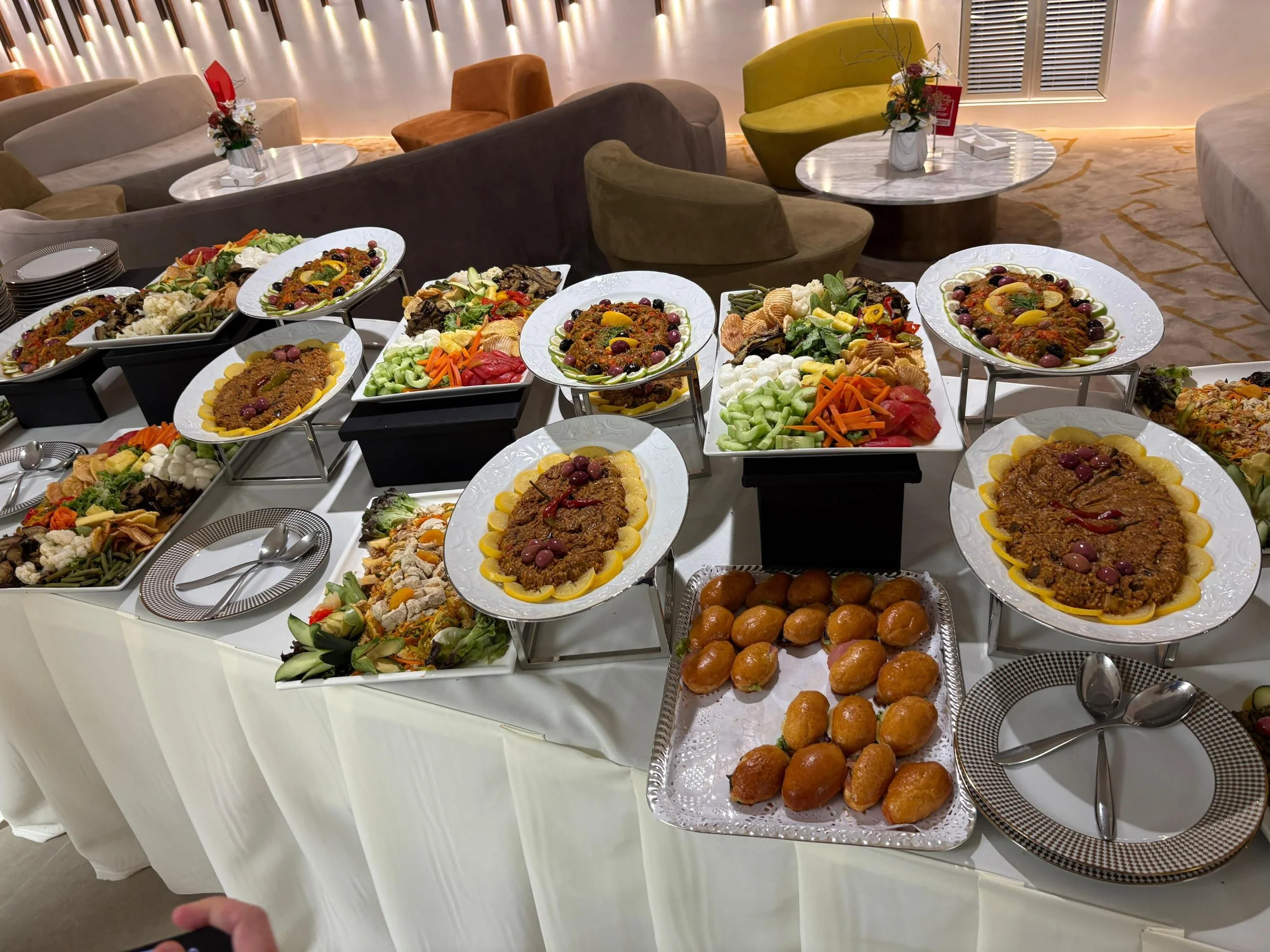 Buffet table with various dishes including salads, meats, and desserts, set in an elegant restaurant or banquet hall.