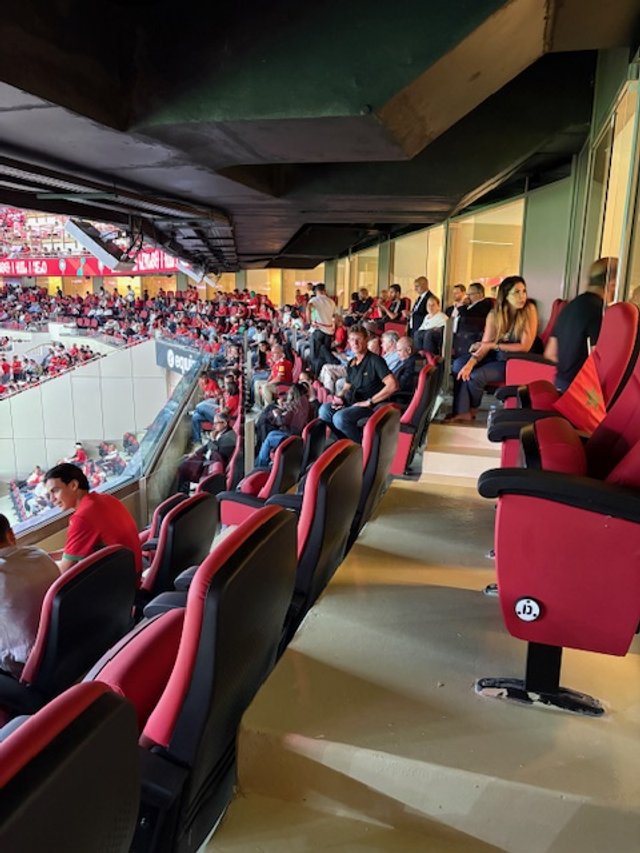 View of arena seating with spectators, some seated and some standing, at a sports event.