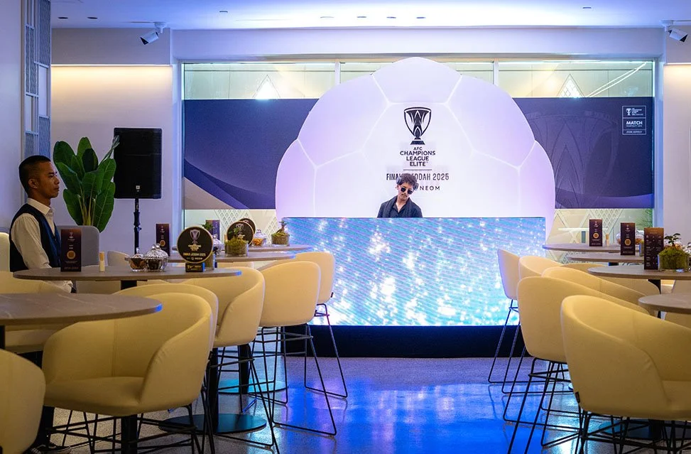 Event space with a large LED screen behind a DJ in MATCH Club Gold Official Hospitality, decorated with a soccer ball theme.