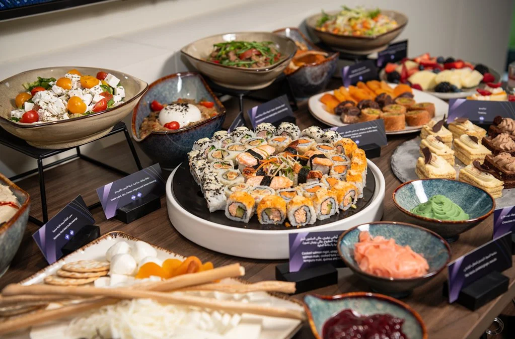 An assortment of salads, sushi, desserts, and dips arranged on a table at a buffet.