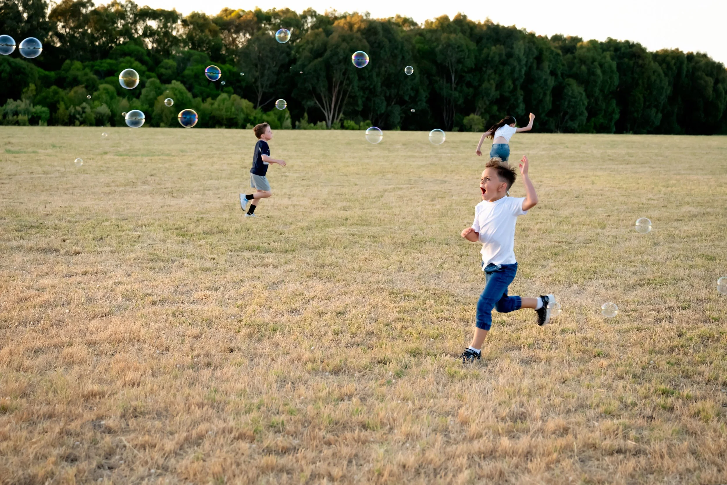 Children running in park after bubbles