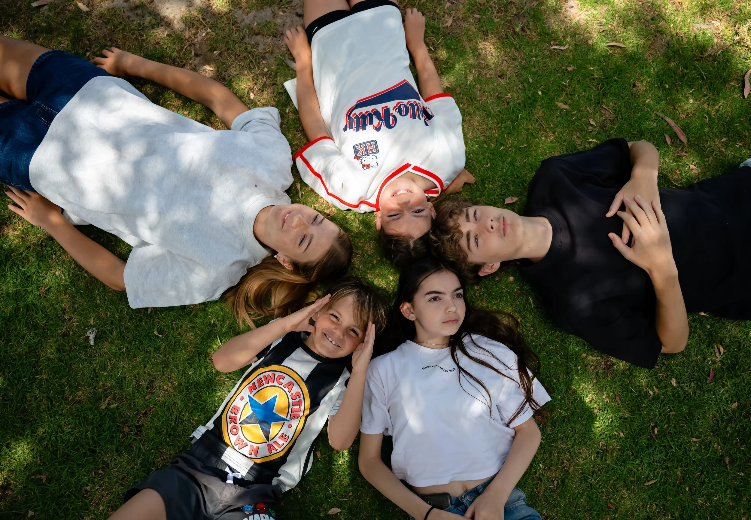 5 Children laying on grass in a circle