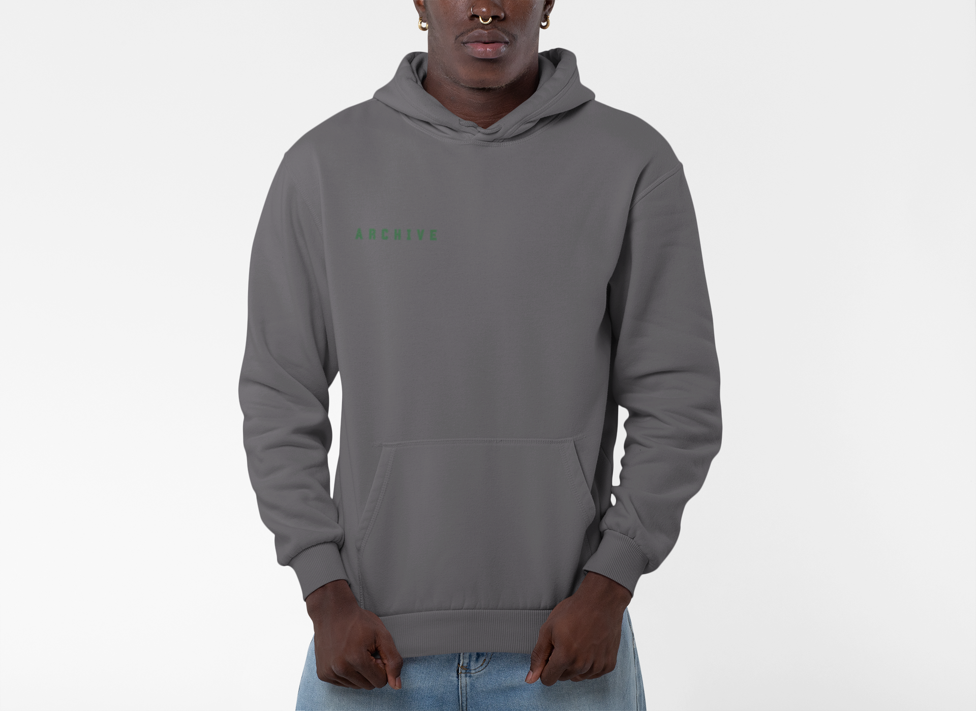 A man wearing a gray hoodie with green text that reads "ARCHIVE" on the left chest, standing against a plain light background.