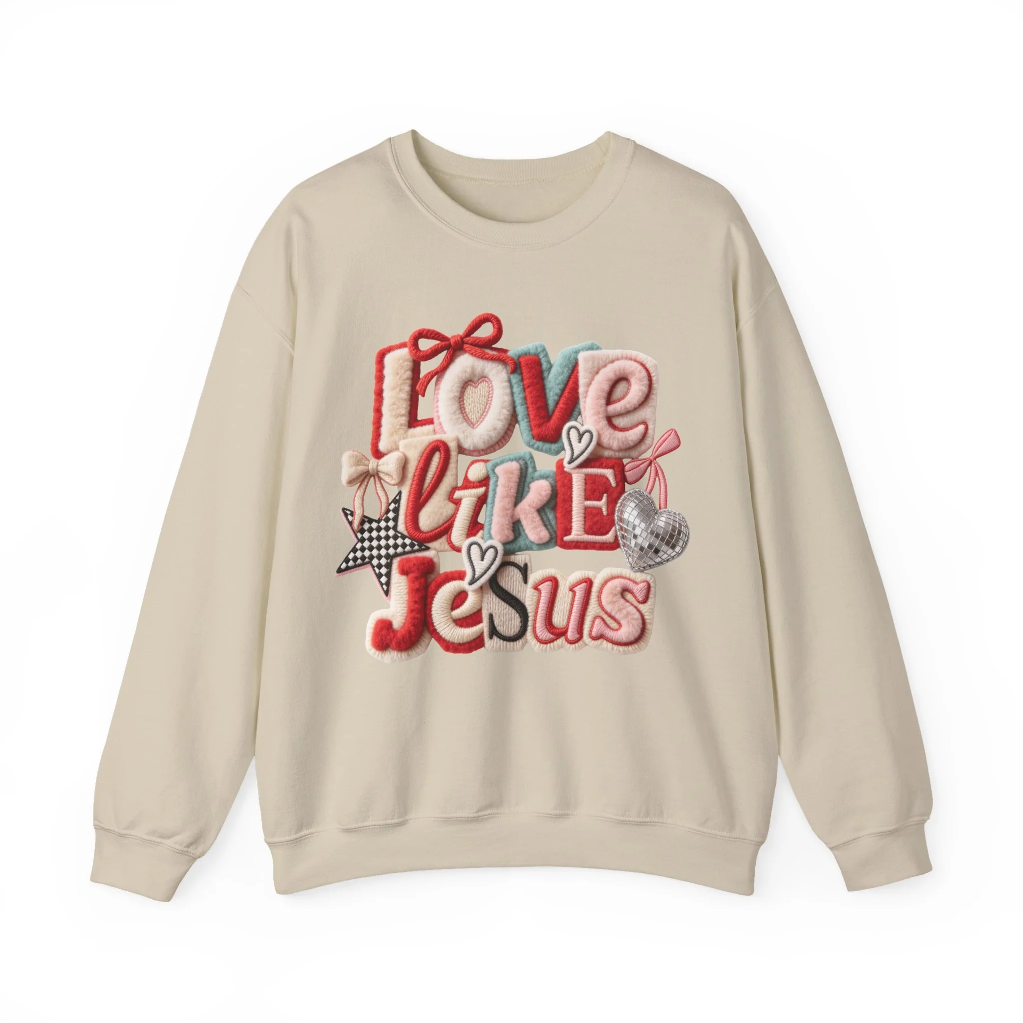 Cream-colored sweatshirt with embroidered words 'Love like Jesus' in various colors and styles, decorated with small embroidered hearts, stars, bows, and a silver disco ball.
