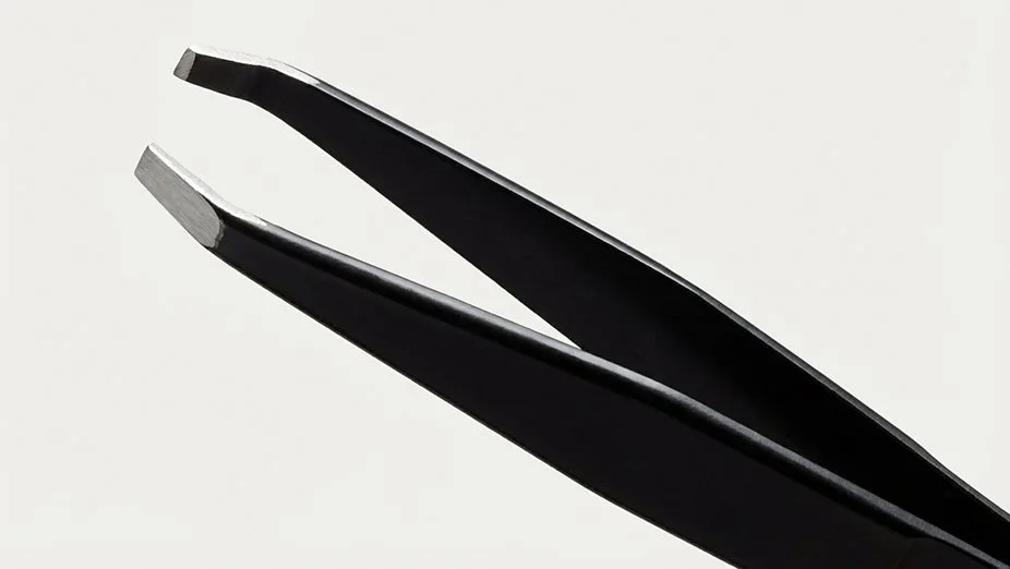 Close-up of black hair splitting hair scissors with silver blades against a light background.
