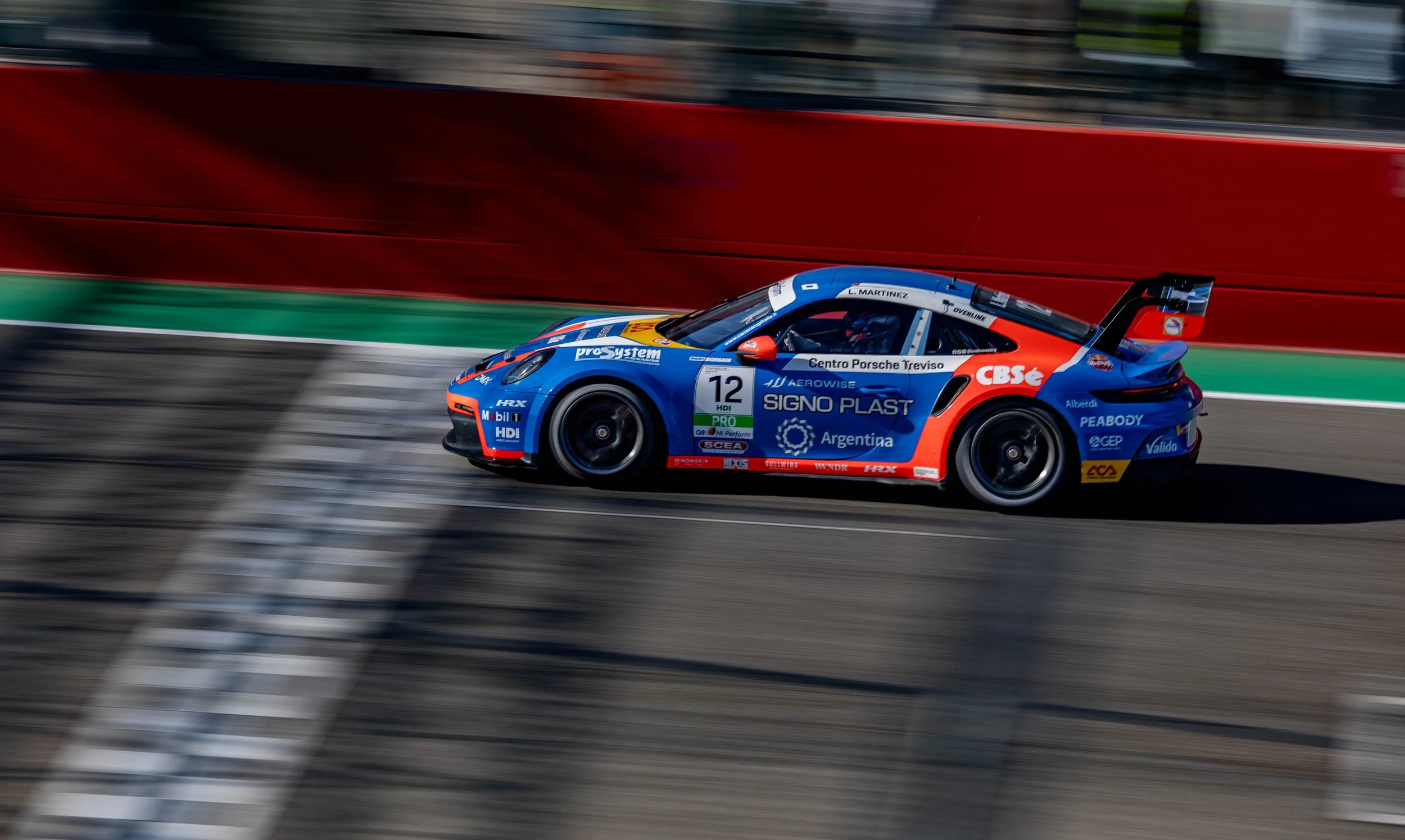 Race car speeding on a track with motion blur, featuring sponsorship logos and the number 12.