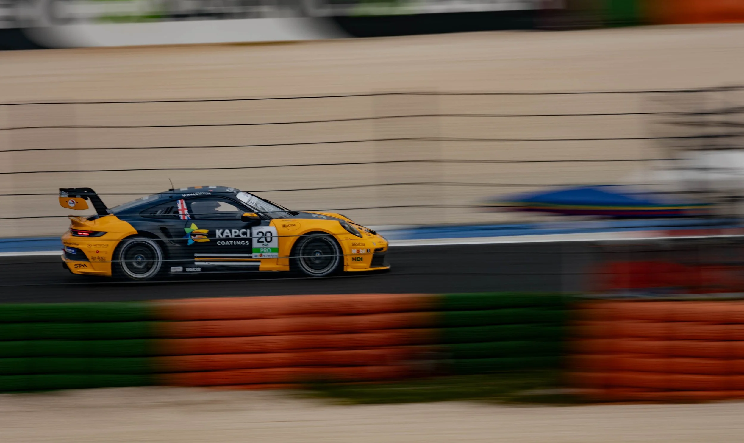 A yellow and black race car moving at high speed on a racetrack with a blurred background.