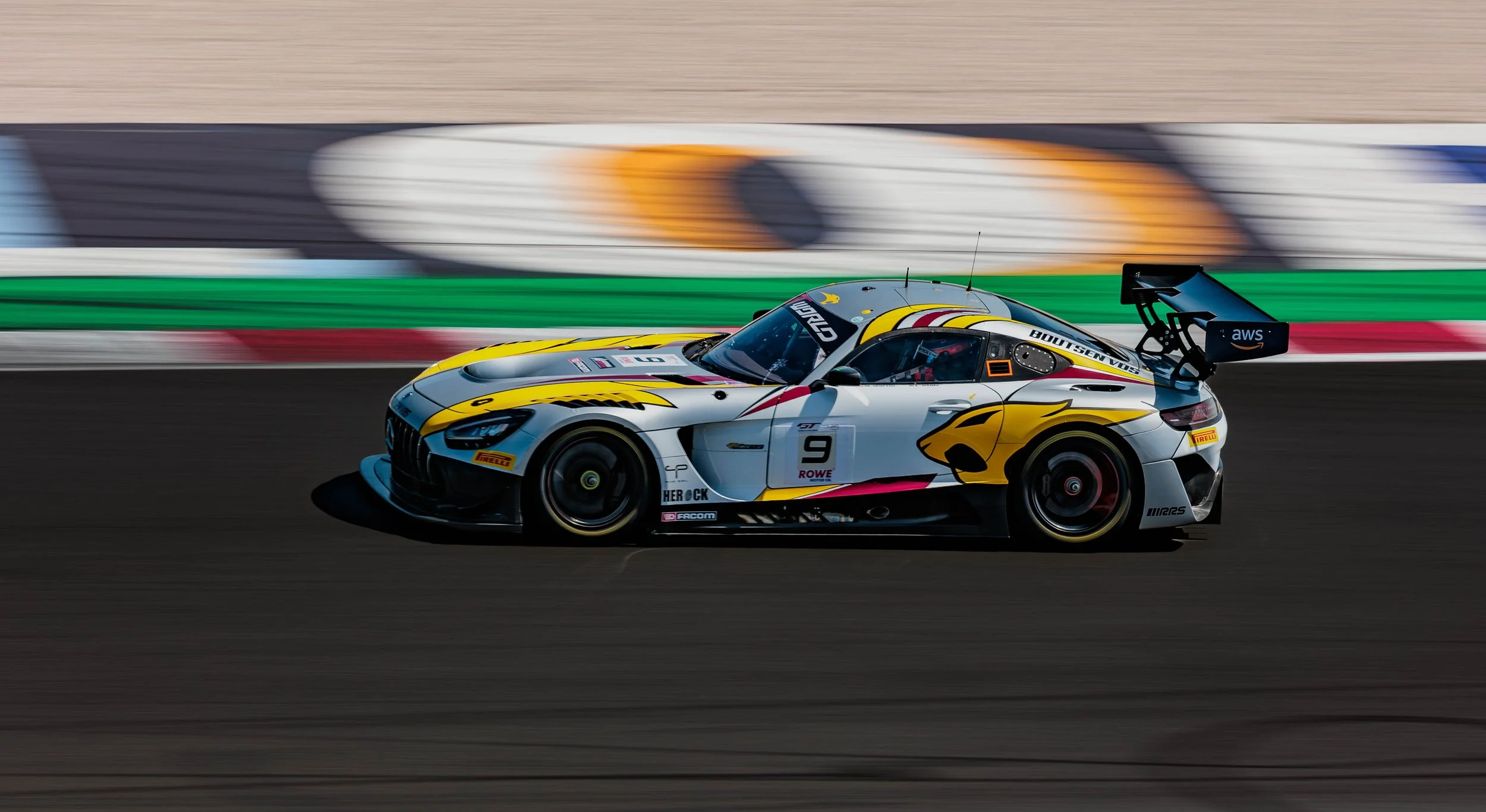 A race car speeding on a track with motion blur, featuring a yellow, white, and black design with a large rear wing.