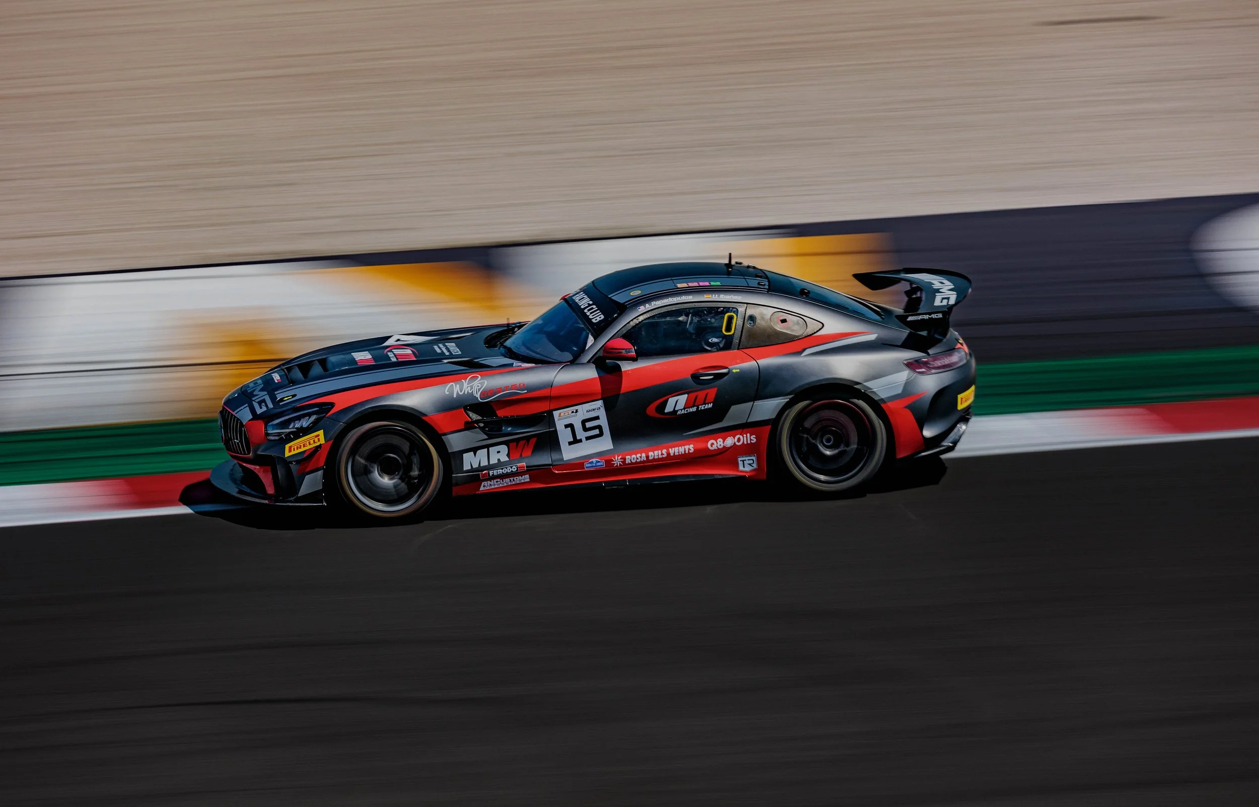 A race car speeding on a racetrack with a blurred background.