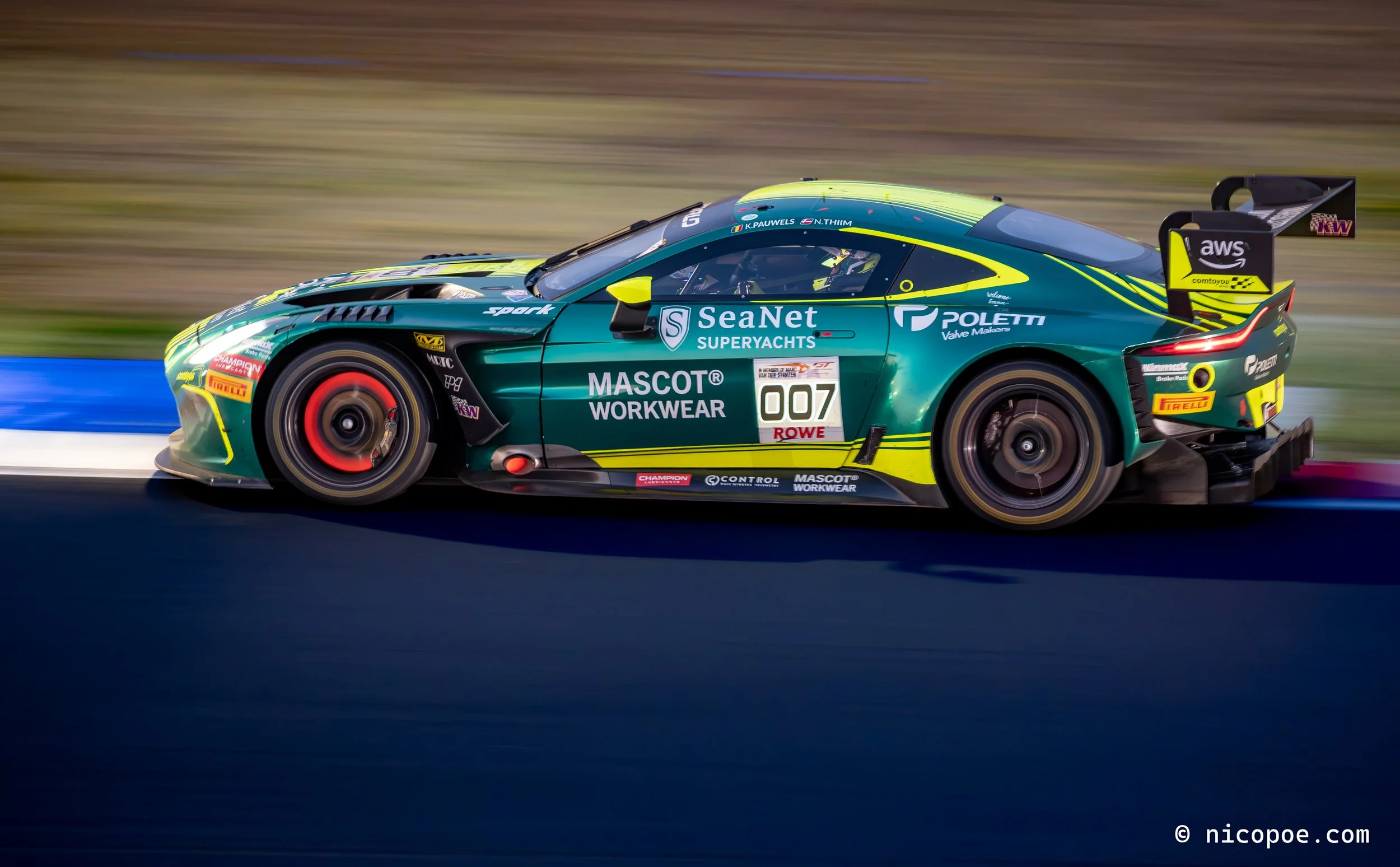 A green race car with yellow accents speeding on a racetrack, with sponsor logos such as SeaNet, Poletti, Pirelli, and AWS, and the number 007 displayed on the side.