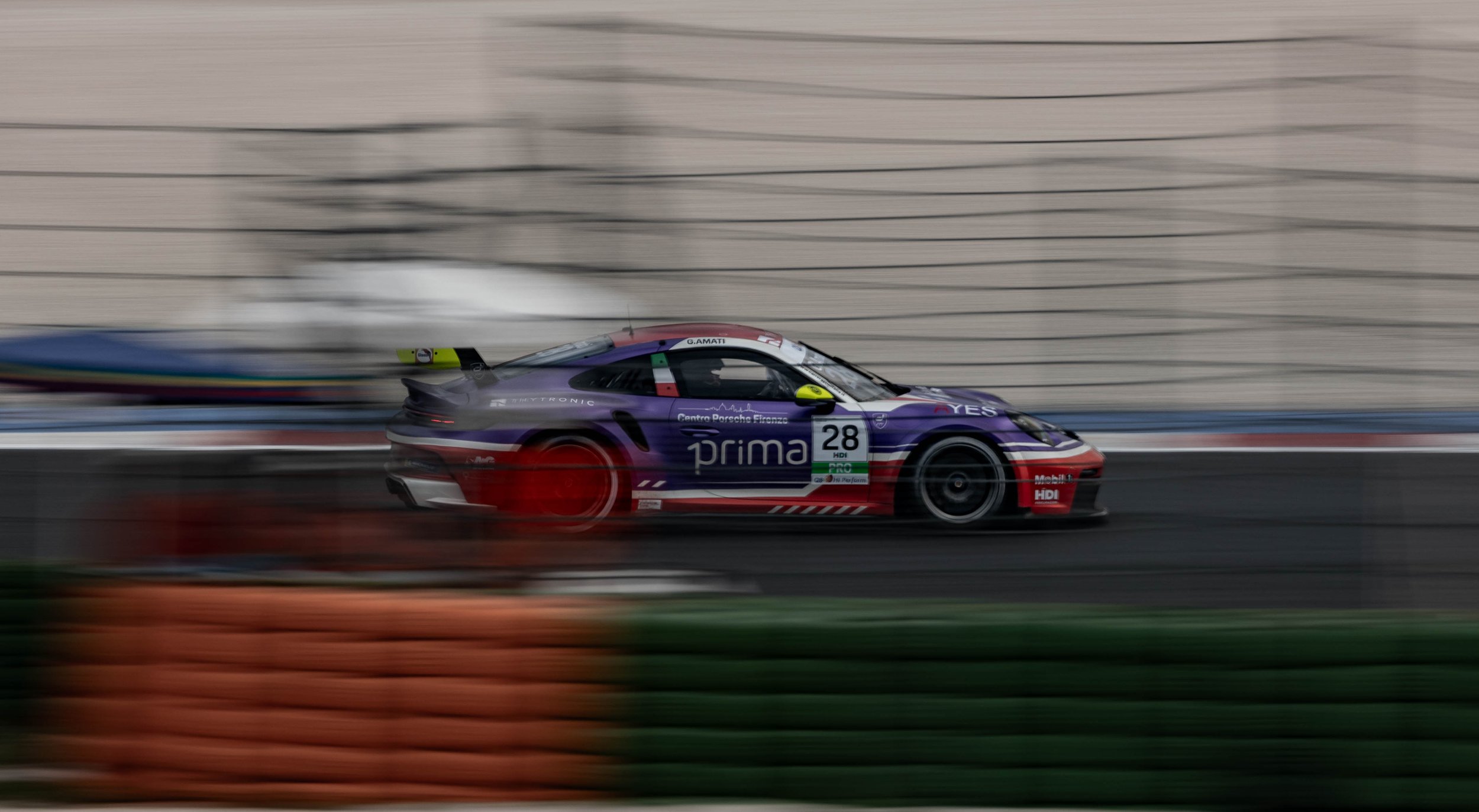 A race car speeding on a track with motion blur, colorful sponsor decals, and a black rear wing.