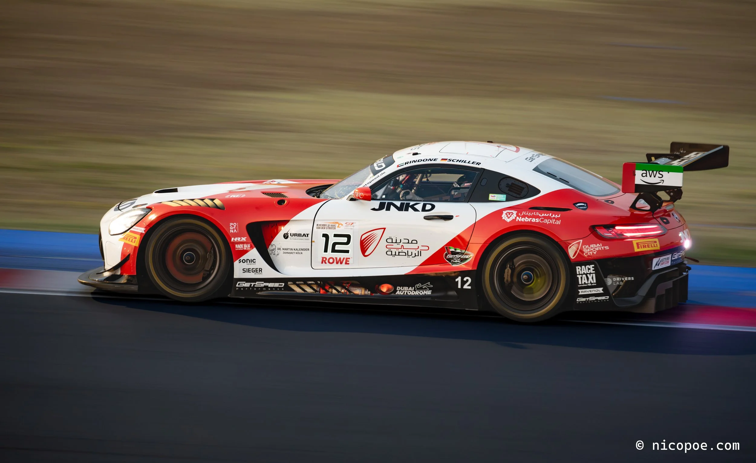 A white and red race car with the number 12 on the side speeding along a race track.