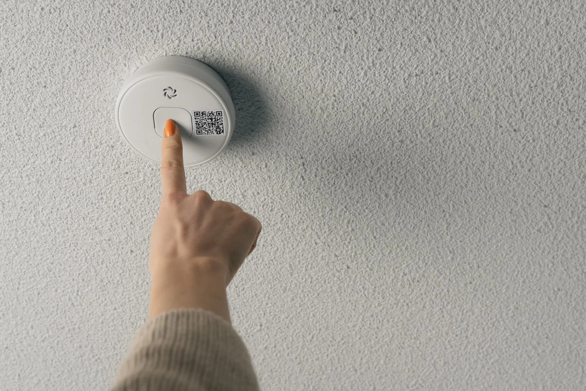 Suvi testaa kattoon asennettua palovaroitinta painamalla siinä olevaa testipainiketta.