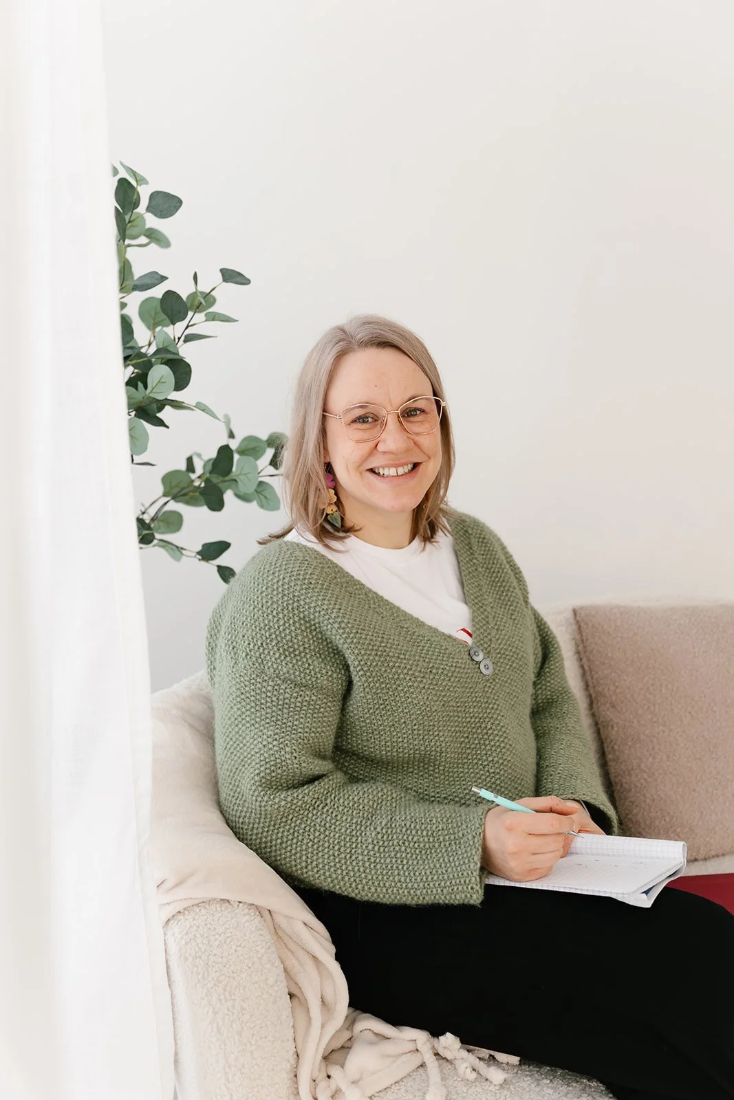 Lempeä Terapiapalvelut terapeutti Pauliina Päivärinta istuu sohvalla ja hymyilee.