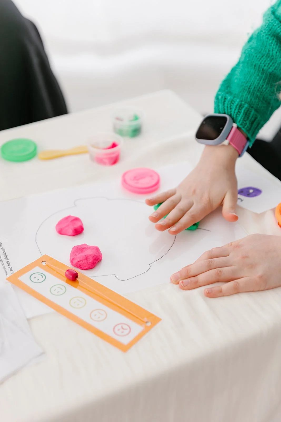 Lapsi painaa muovailuvahaa pöytää vasten Lempeä Terapiapalvelut toimintaterapiassa.