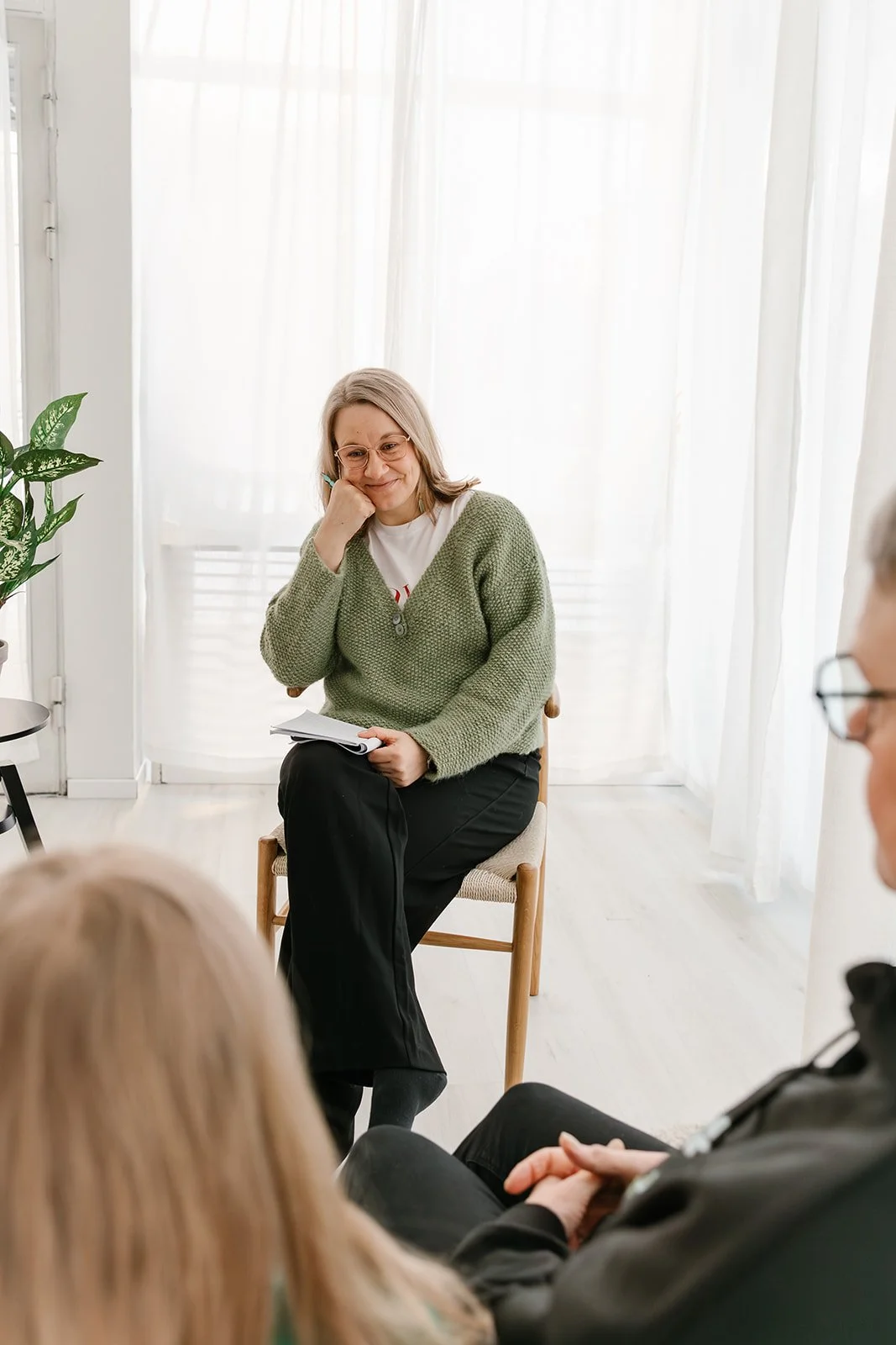 Terapeutti istuu asiakkaita vastapäätä ja hymyilee.