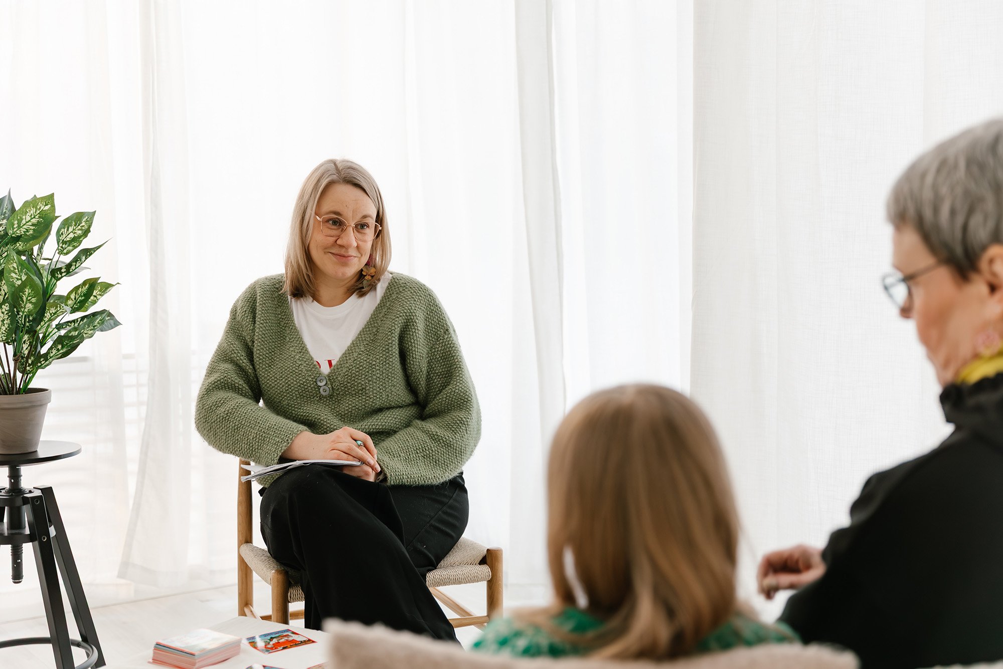 Lempeä Terapiapalvelut asiakastilanne, jossa terapeutti istuu asiakkaita vastapäätä hymyillen.