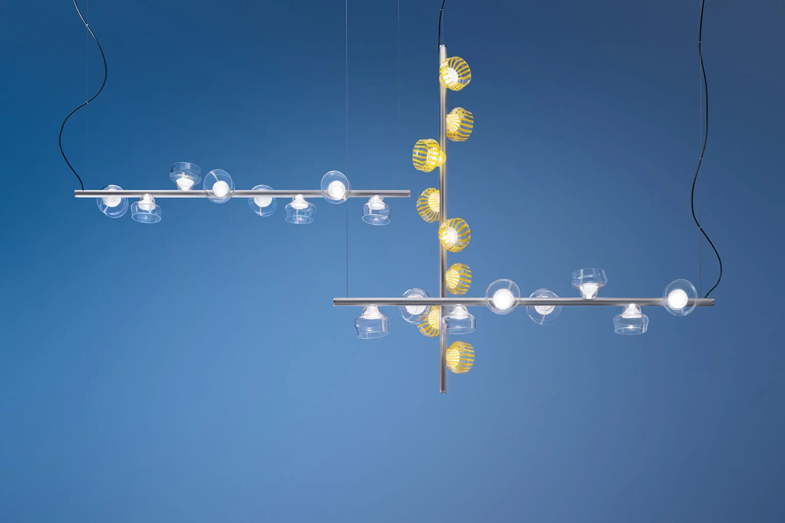 Modern chandelier with glass and yellow striped lamps against a blue background.