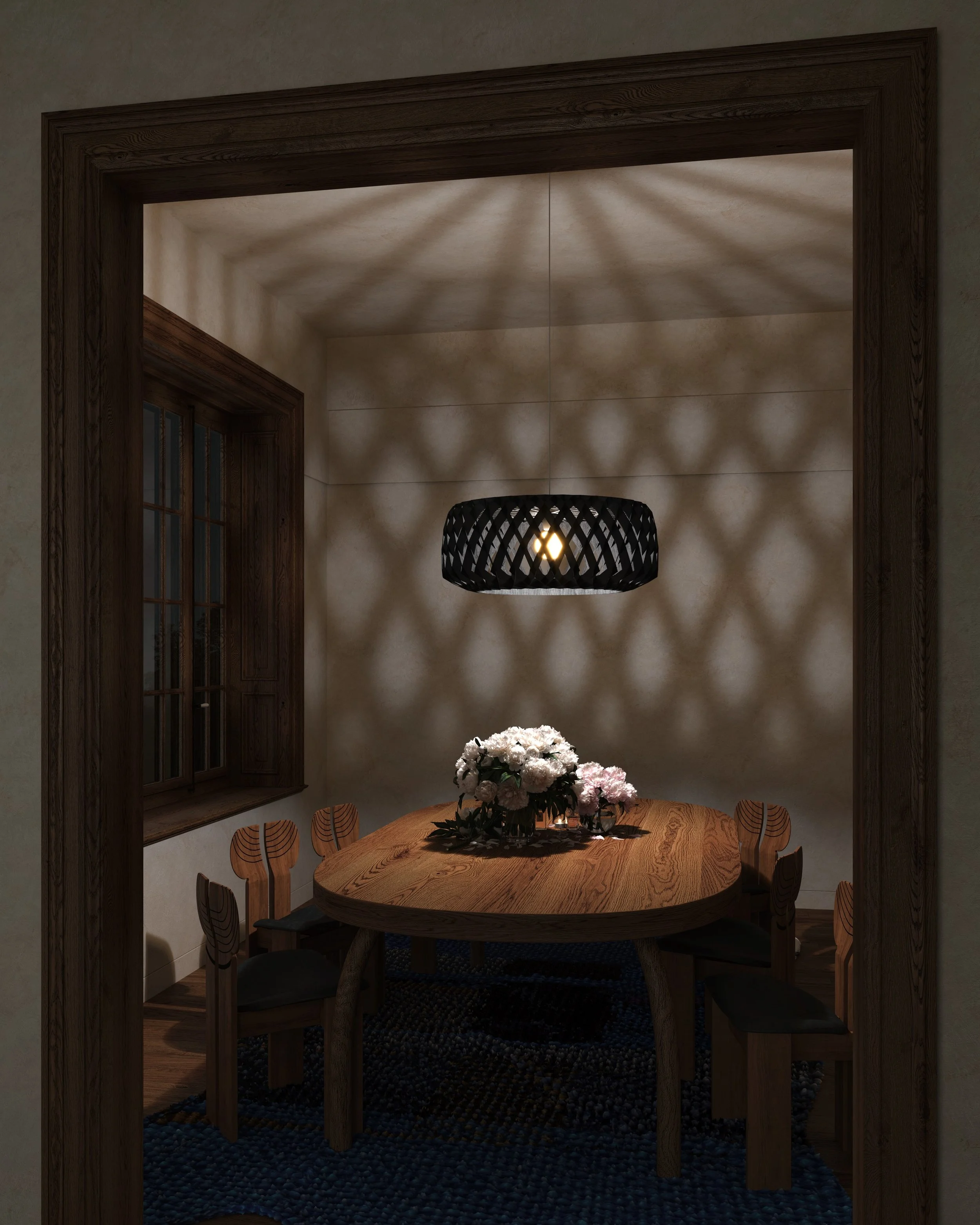 A cozy dining room featuring a wooden oval table with a floral centerpiece. Above, a black woven pendant light casts patterned shadows on the beige textured walls. There's a window with wooden framing on the left and a dark rug underneath the table.
