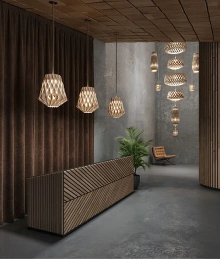 Modern interior lobby with pendant lights, a leather chair, potted plant, and textured walls.