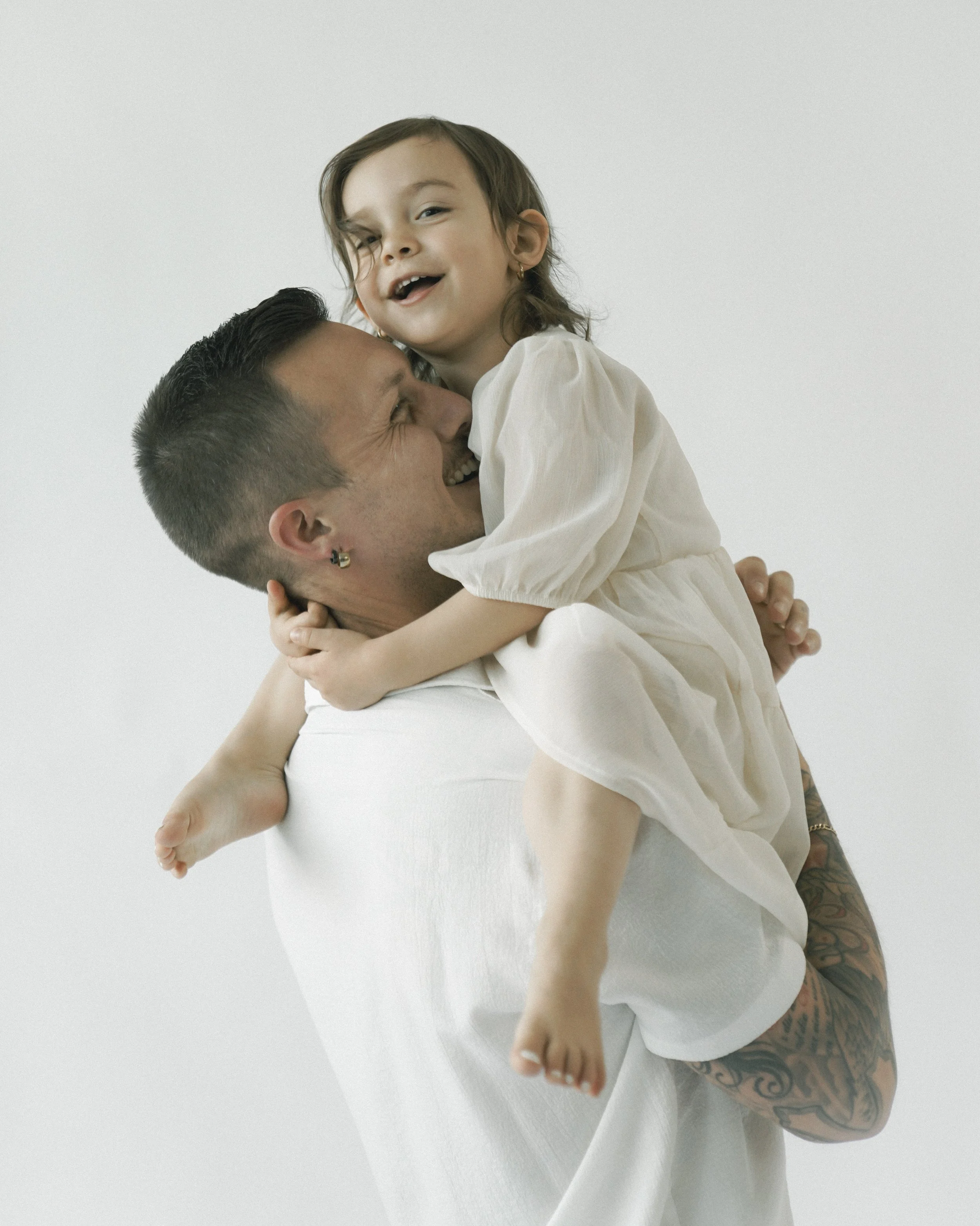 Studio-Familienportrait eines jungen Vaters mit Kind vor neutralem Hintergrund, fotografiert von Fotografin Salome Peter in Wil