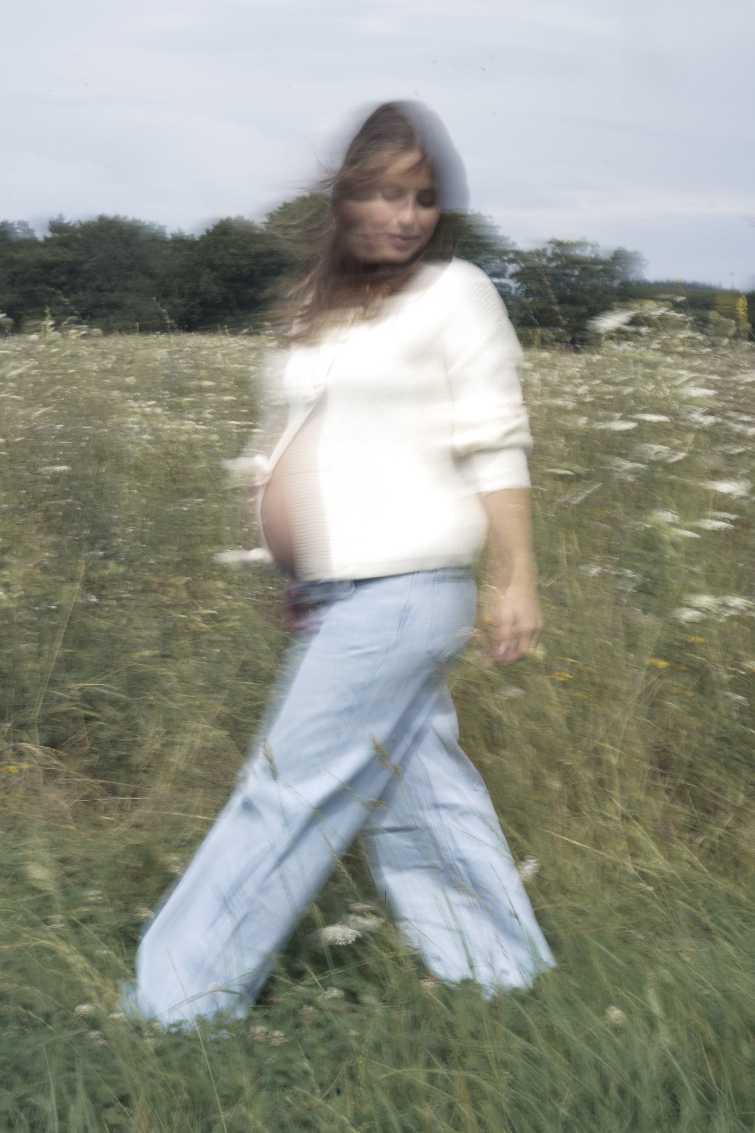 Porträt einer schwangeren Frau auf einer Blumenwiese, fotografiert von Fotografin Salome Peter