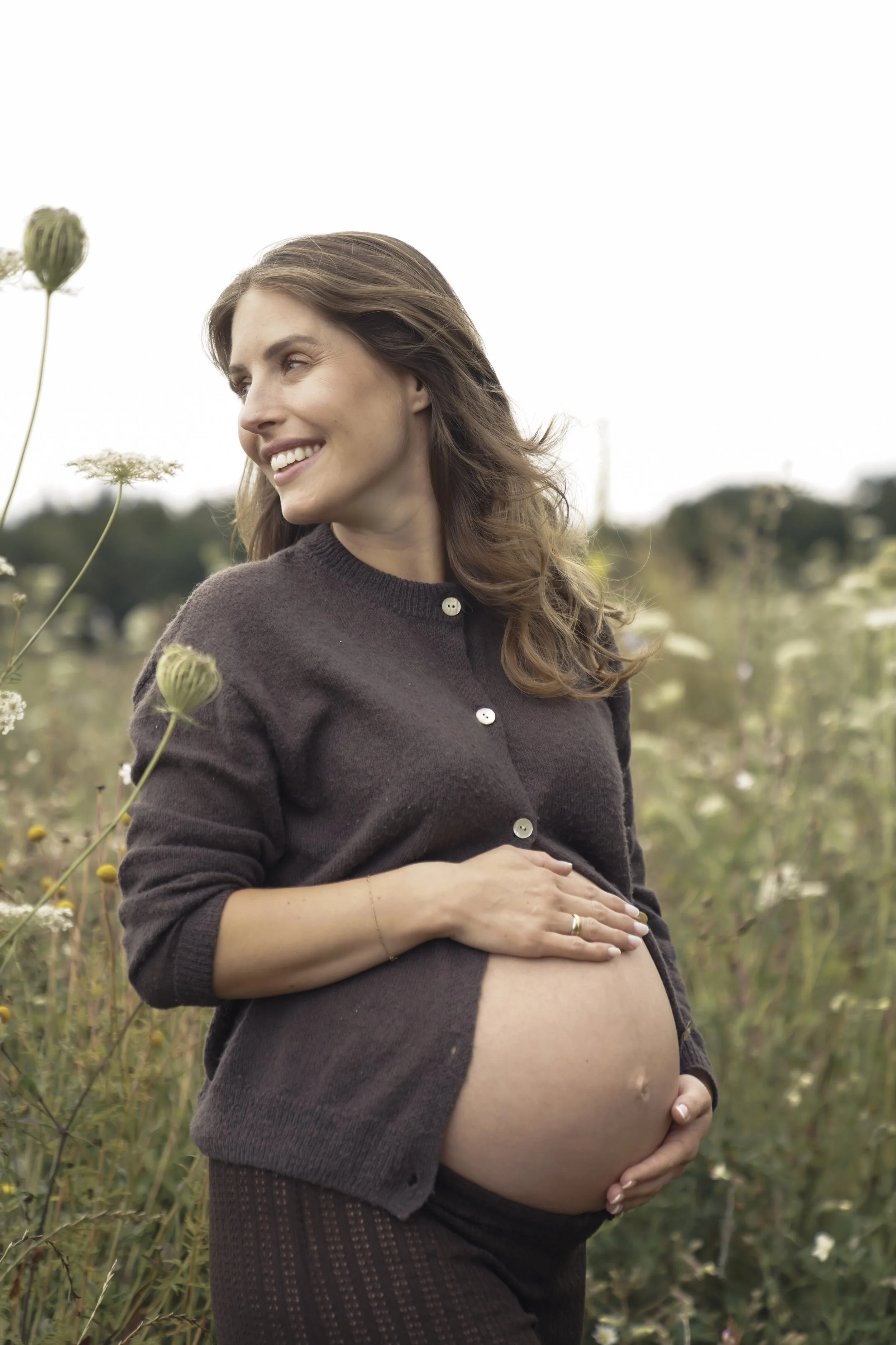 Porträt einer schwangeren Frau auf einer Blumenwiese, fotografiert von Fotografin Salome Peter