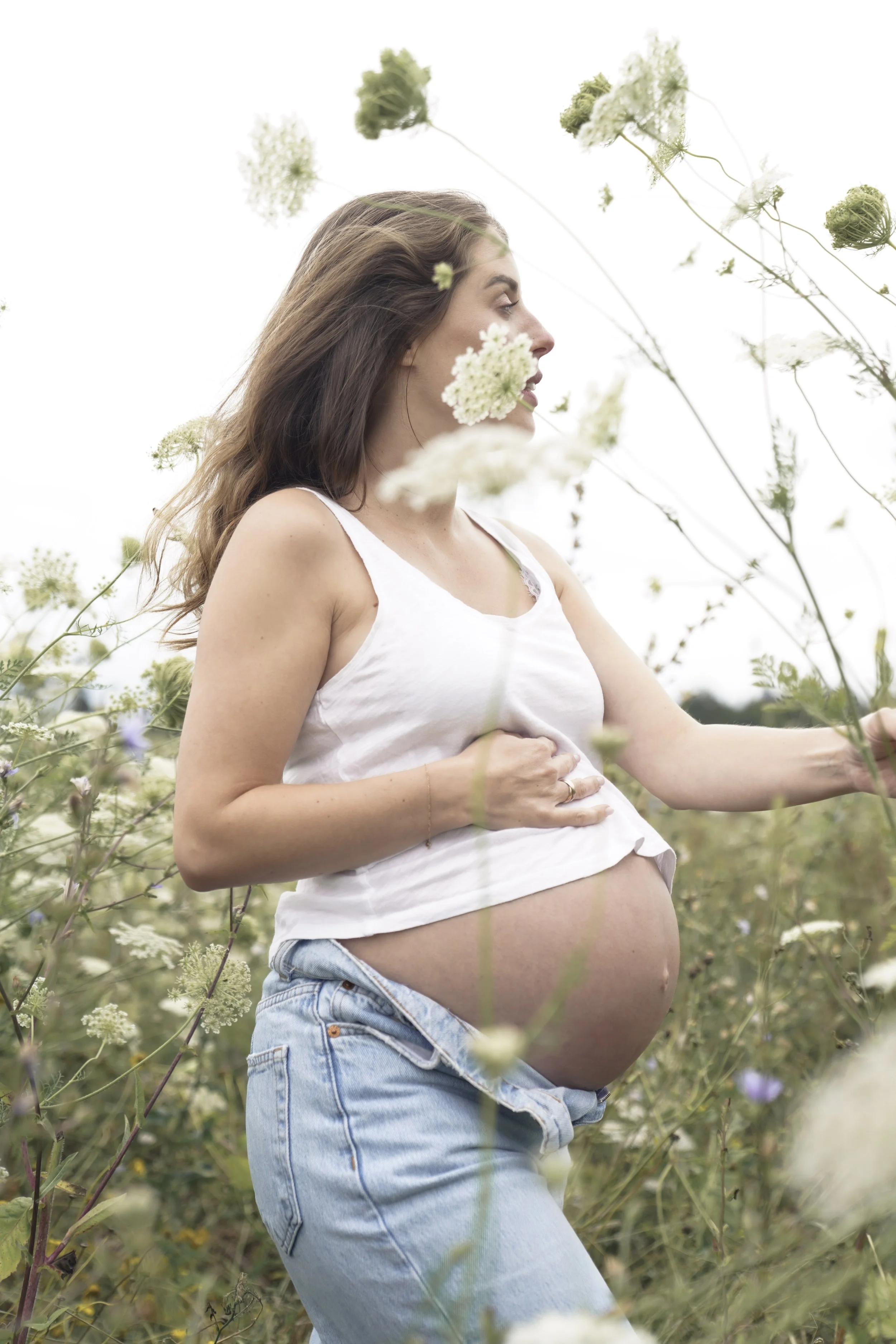 Porträt einer schwangeren Frau auf einer Blumenwiese, fotografiert von Fotografin Salome Peter