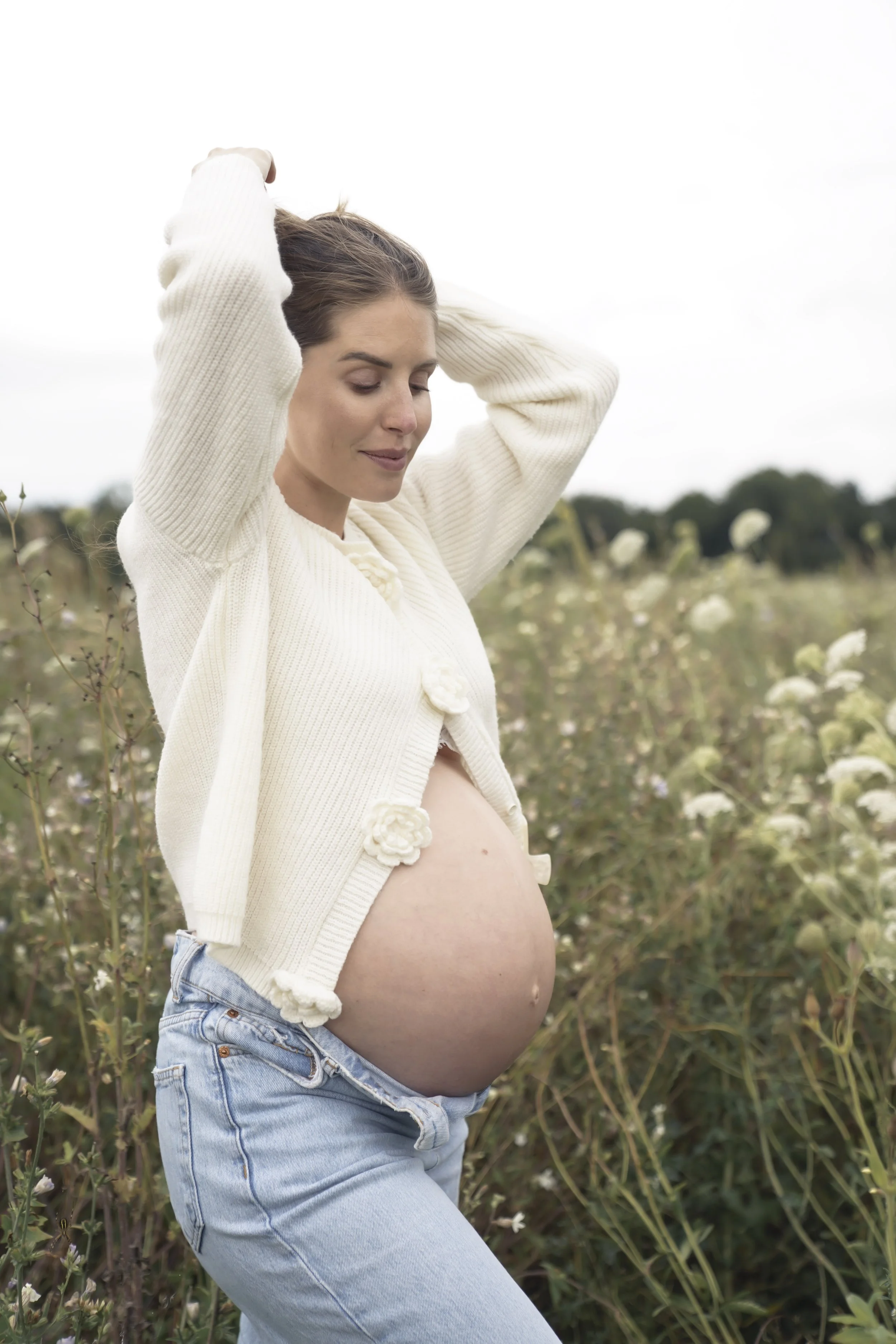 Porträt einer schwangeren Frau auf einer Blumenwiese, fotografiert von Fotografin Salome Peter