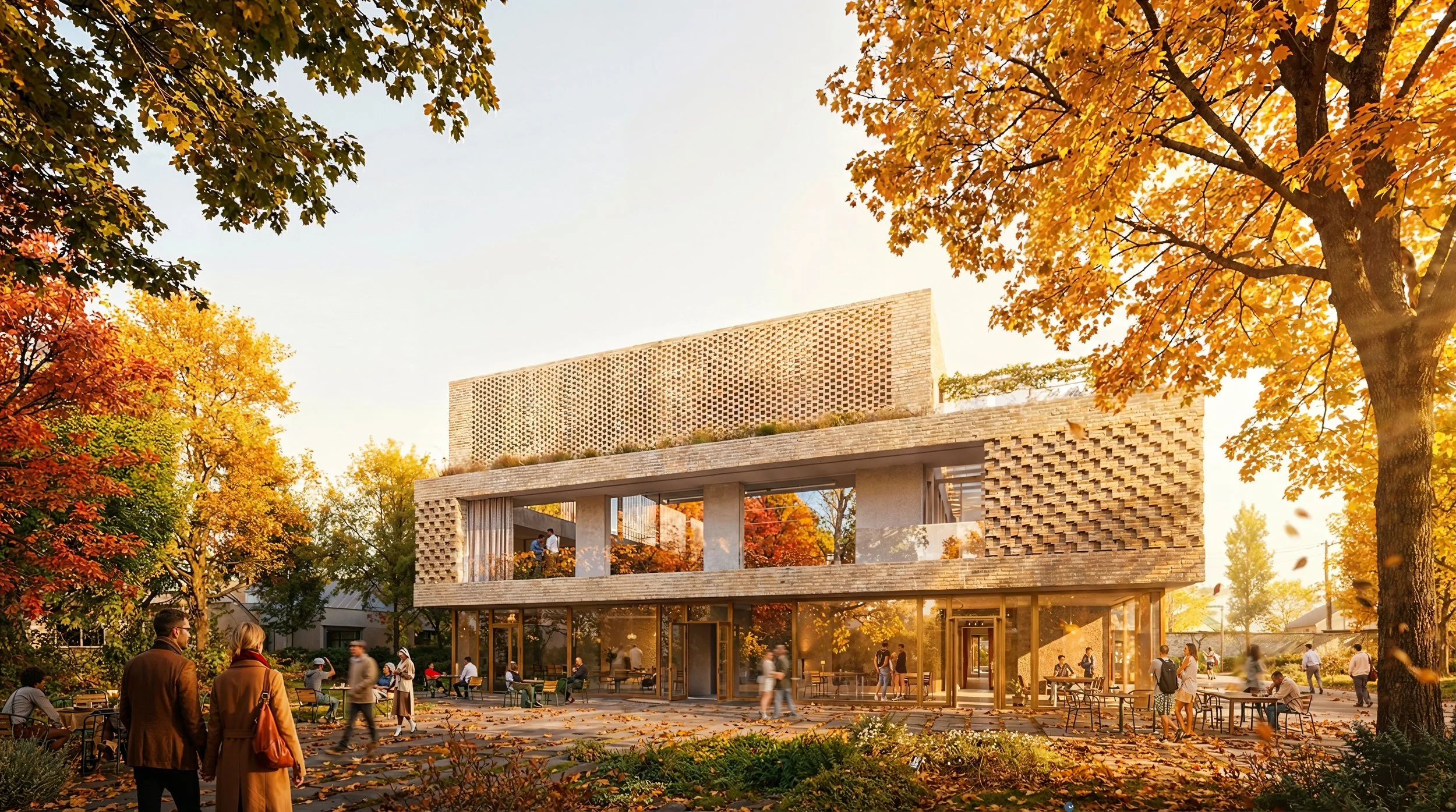 Un immeuble moderne en béton avec des murs décorés de motifs en relief, entouré d’arbres aux feuilles d’automne, avec des gens qui se promènent et s’assoient à l’extérieur, dans un cadre urbain en fin d’après-midi.