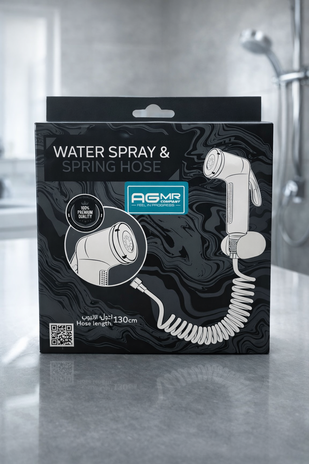 Black and white box packaging for a water spray and spring hose, featuring a diagram of the device, the brand name AGMR, and a QR code, with a reflection on a smooth surface.