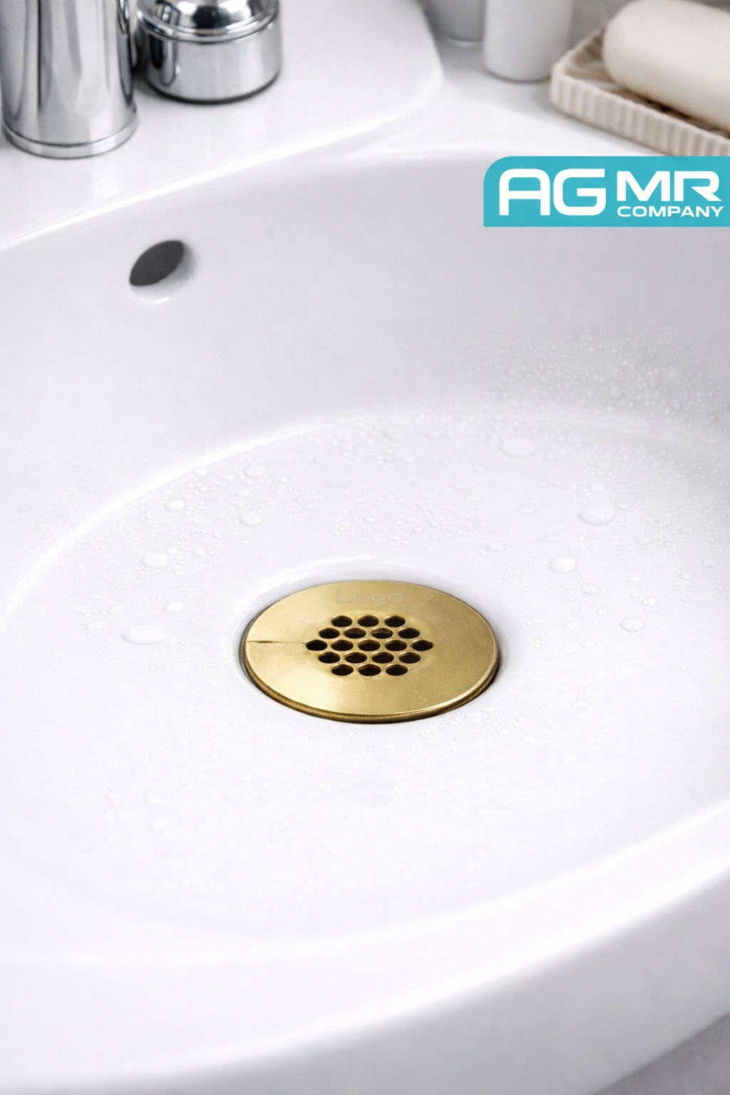 Close-up of a white sink with a metallic drain cover and water droplets, featuring a blue logo that says AG MR Company.