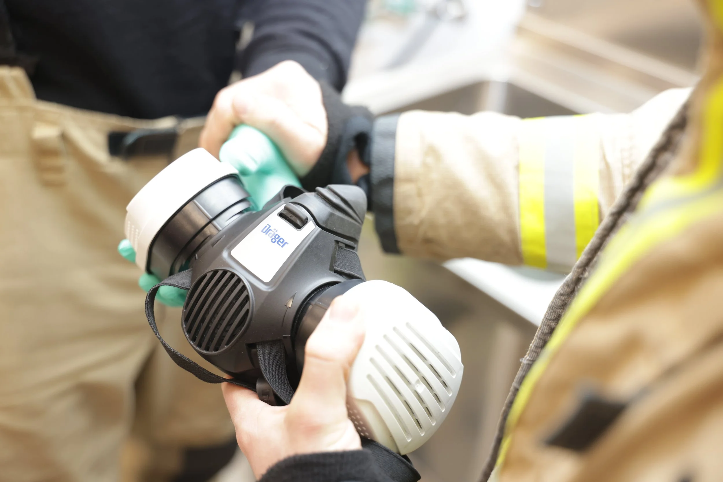 Person bruker en drill på en treflate. Personen har på seg arbeidsklær og hansker.