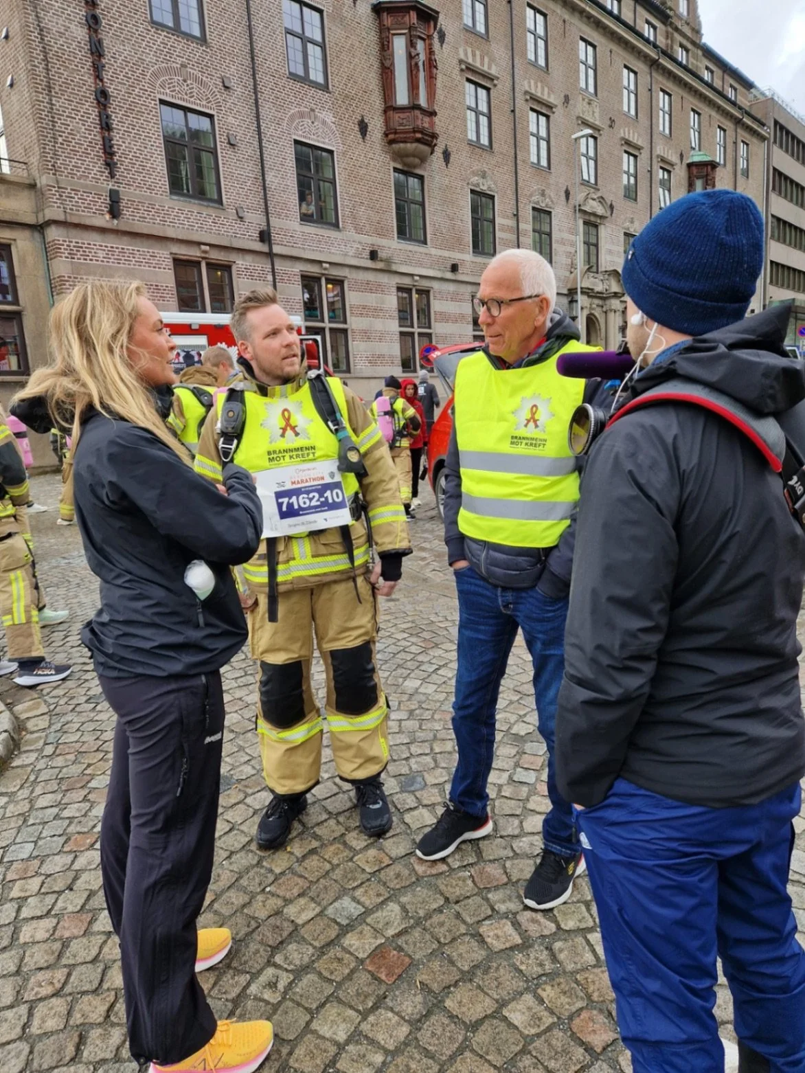 Firemenn og en kvinne snakker sammen på gaten under et arrangement.