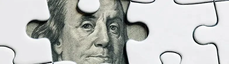 Partial image of a puzzle with a piece missing, revealing a dollar bill featuring a woman's face.