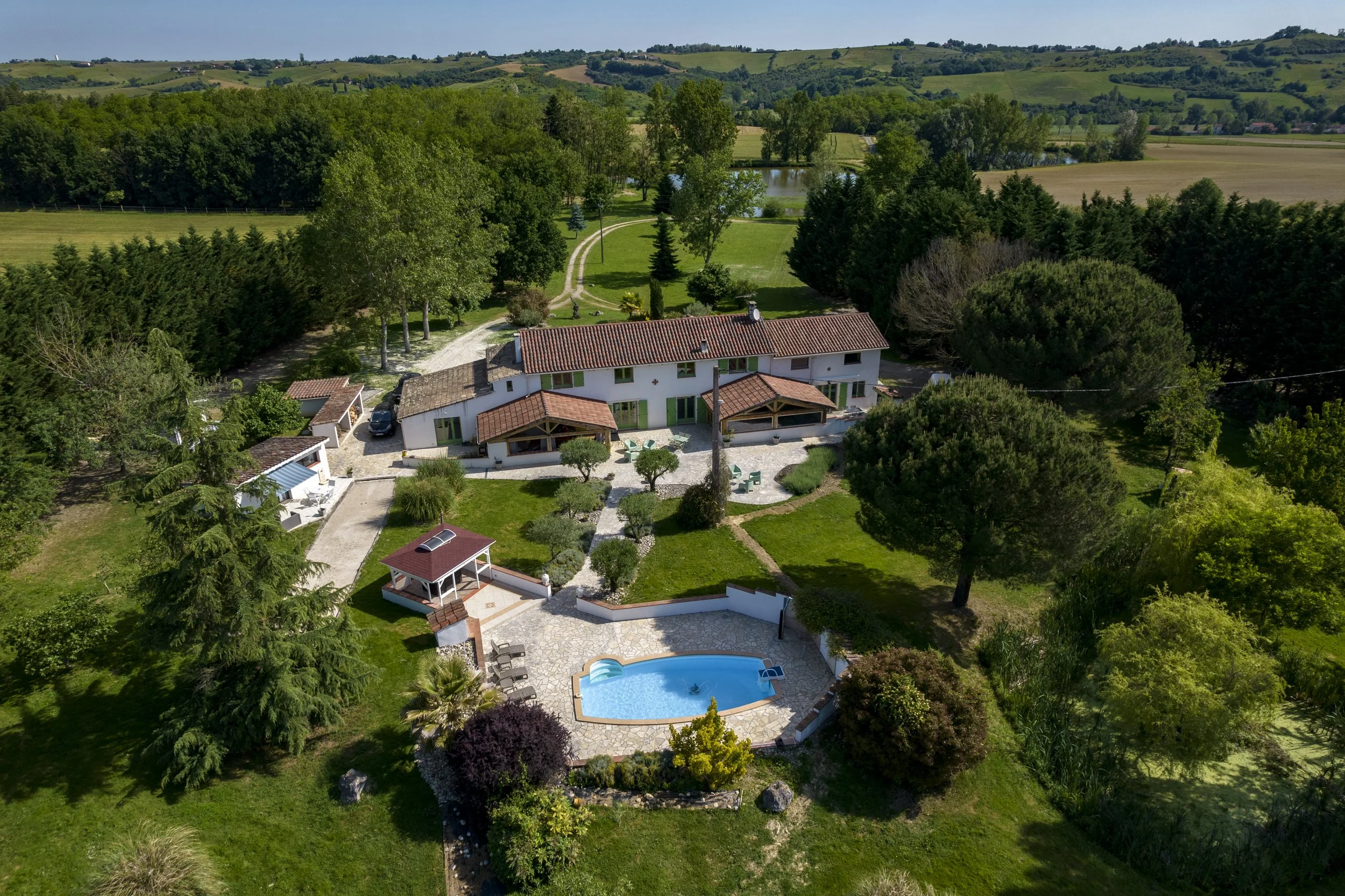 vue aérienne d'une résidence avec piscine, entourée d'arbres et de verdure dans un paysage rural.