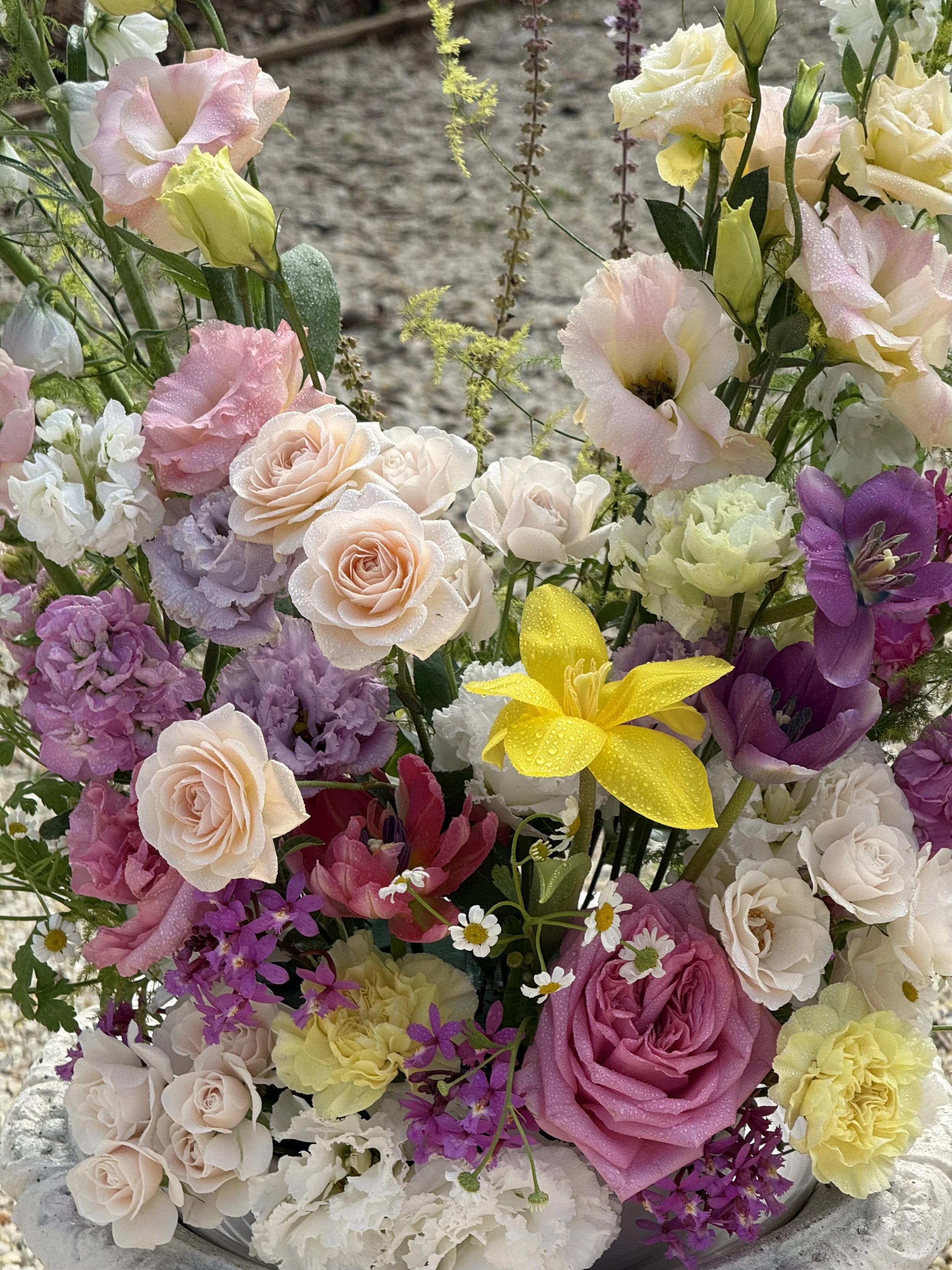 A colorful bouquet of fresh flowers including roses, lilies, and other blooms with dew or rain droplets on petals for a wedding