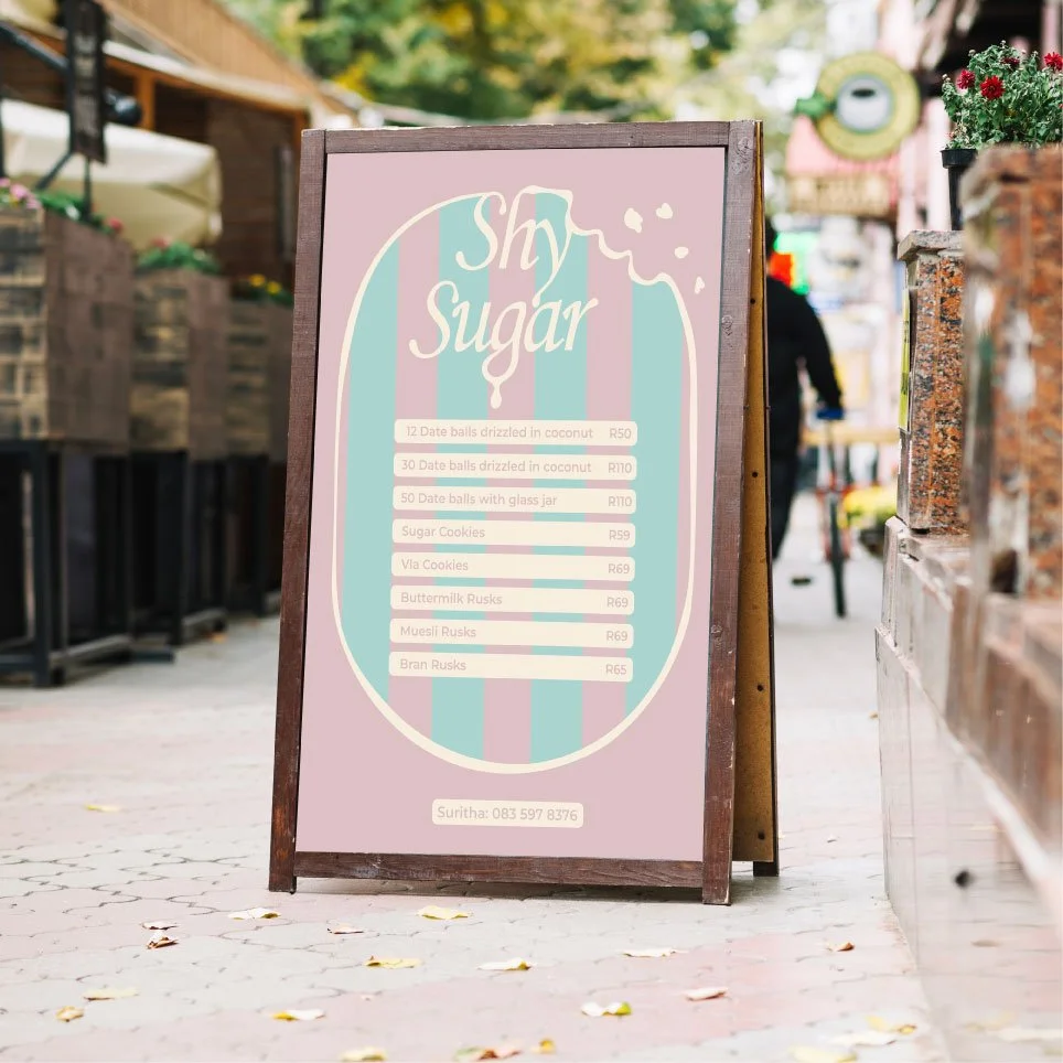 Outdoor sign advertising various sweet treats like date balls, cookies, and rusks at a bakery named 'Shy Sugar'.