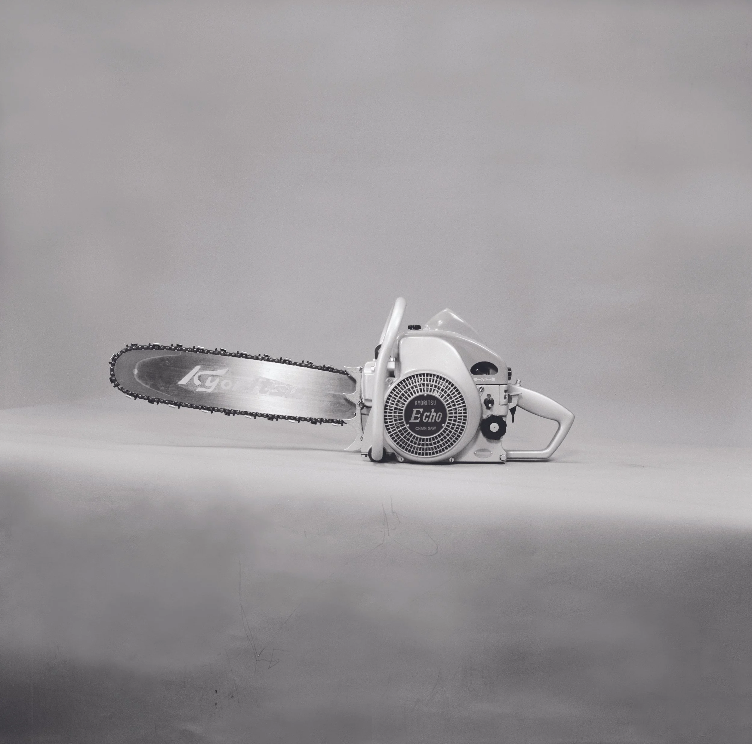 Zgodovinska črno-bela fotografija prve motorne žage ECHO CS-80, ki prikazuje začetek razvoja ročnih motornih orodij blagovne znamke ECHO.