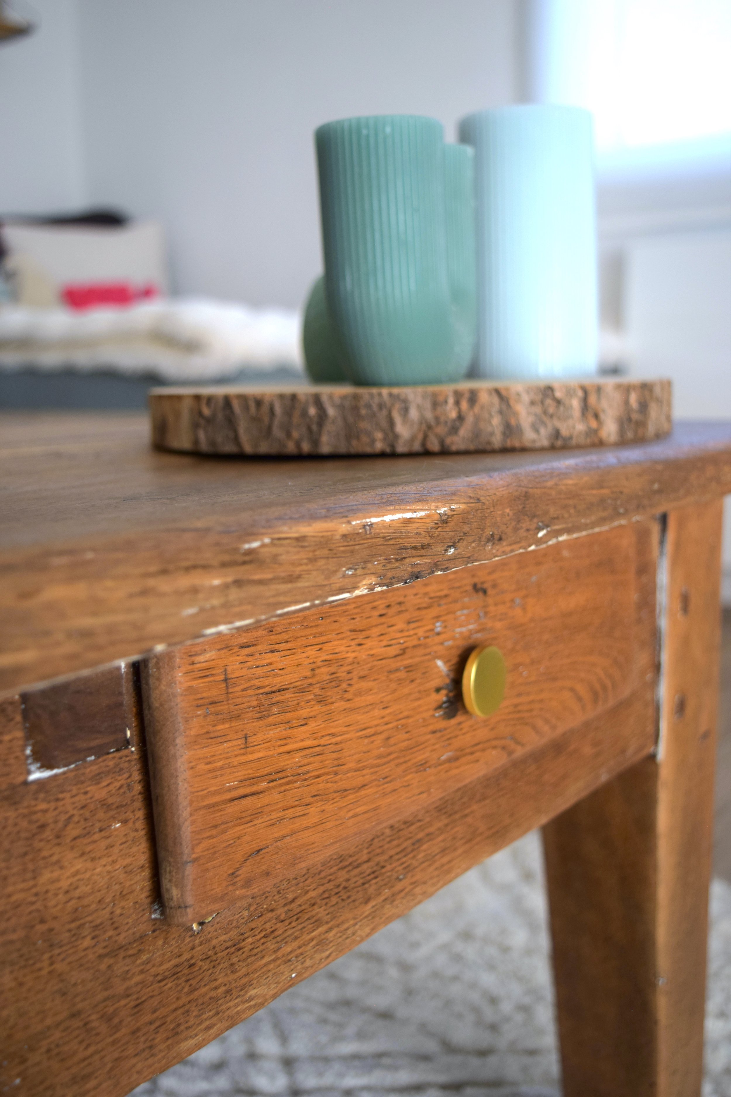 gros plan sur une table basse chinée en bois massif en joli détail, bougies vertes