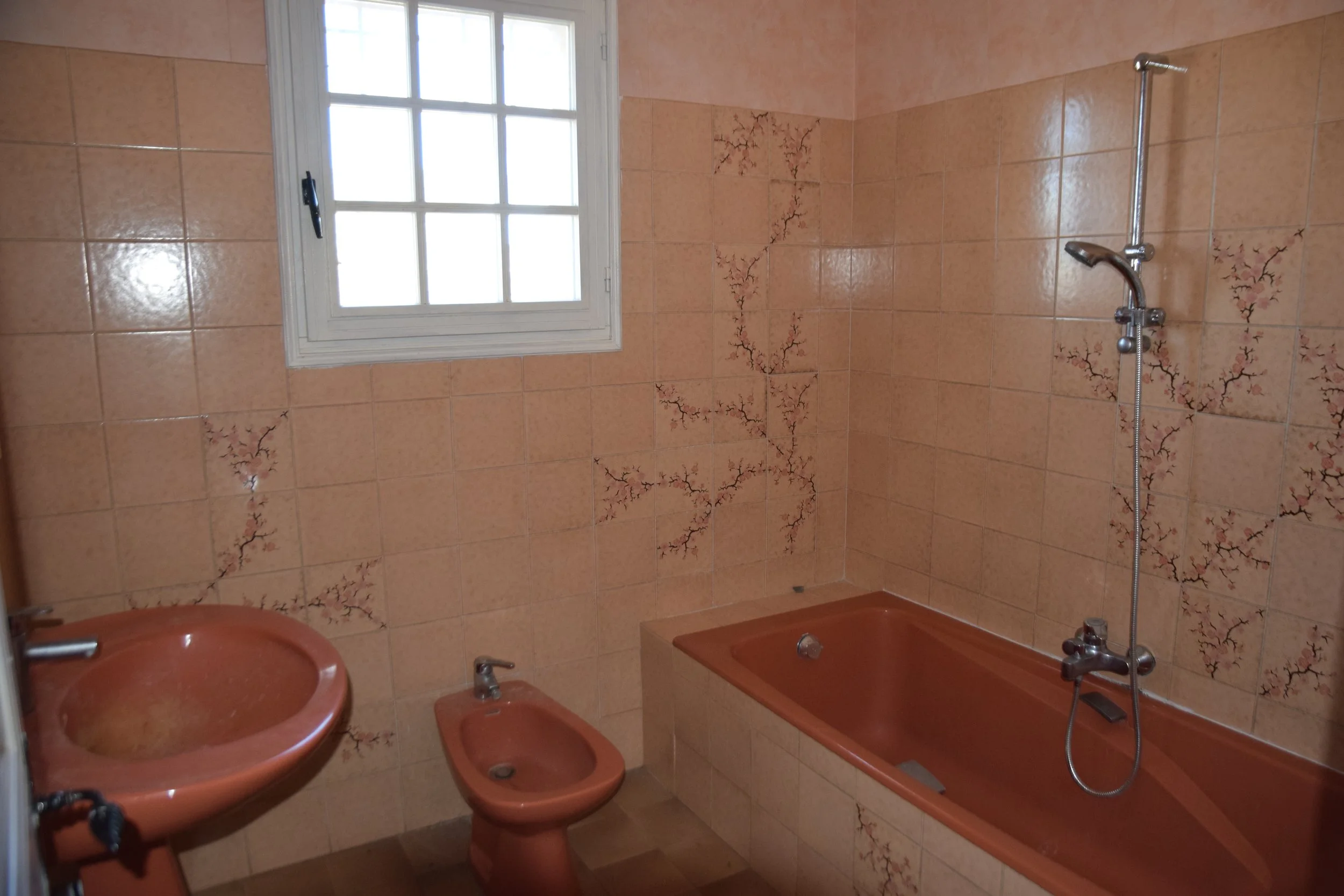 salle de bain vintage avec bidet rose, baignoire et lavabo rose, carrelage fleur de cerisier