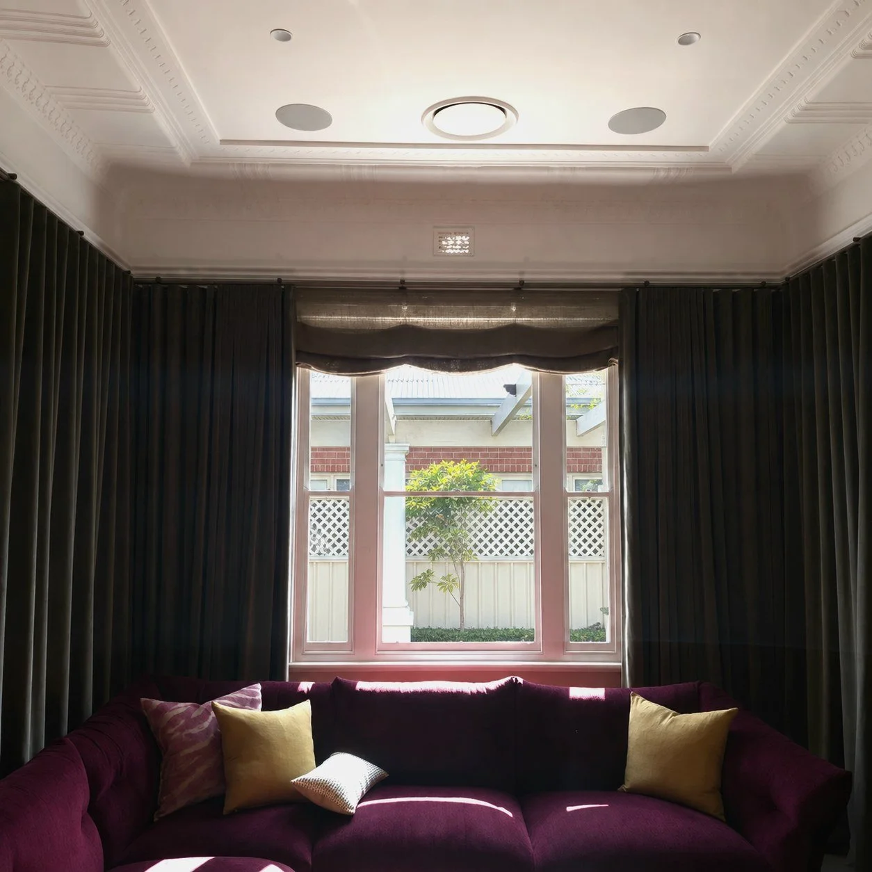 Floor to ceiling olive velvet curtains with a linen roman blind in a Perth living room