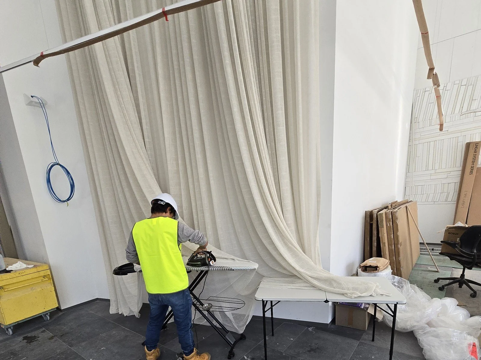 Glorious Home Decor installer steaming floor to ceiling sheer curtains on site at a commercial fit-out in Perth
