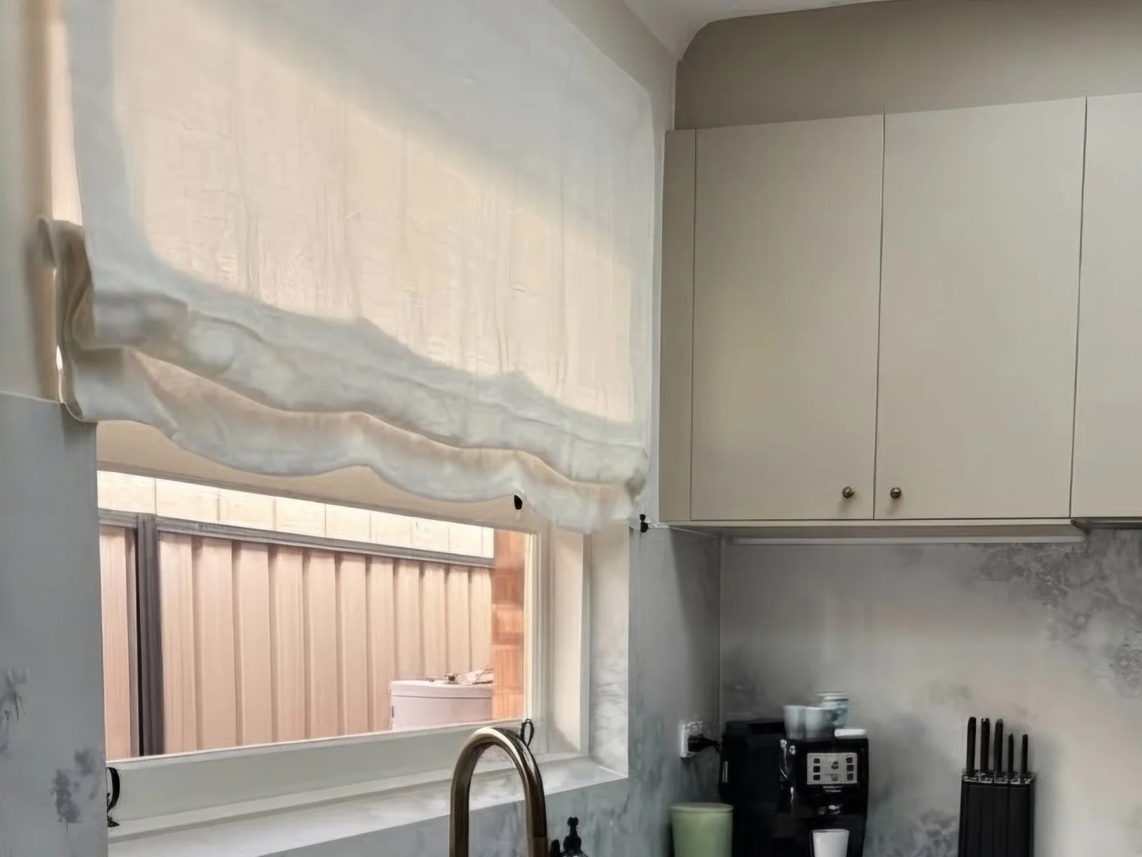 Linen roman blind with a scalloped hem over a kitchen window