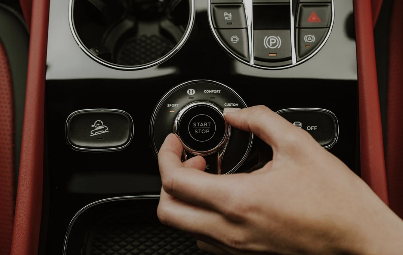 Person turning a drive mode selector dial in a car's center console.