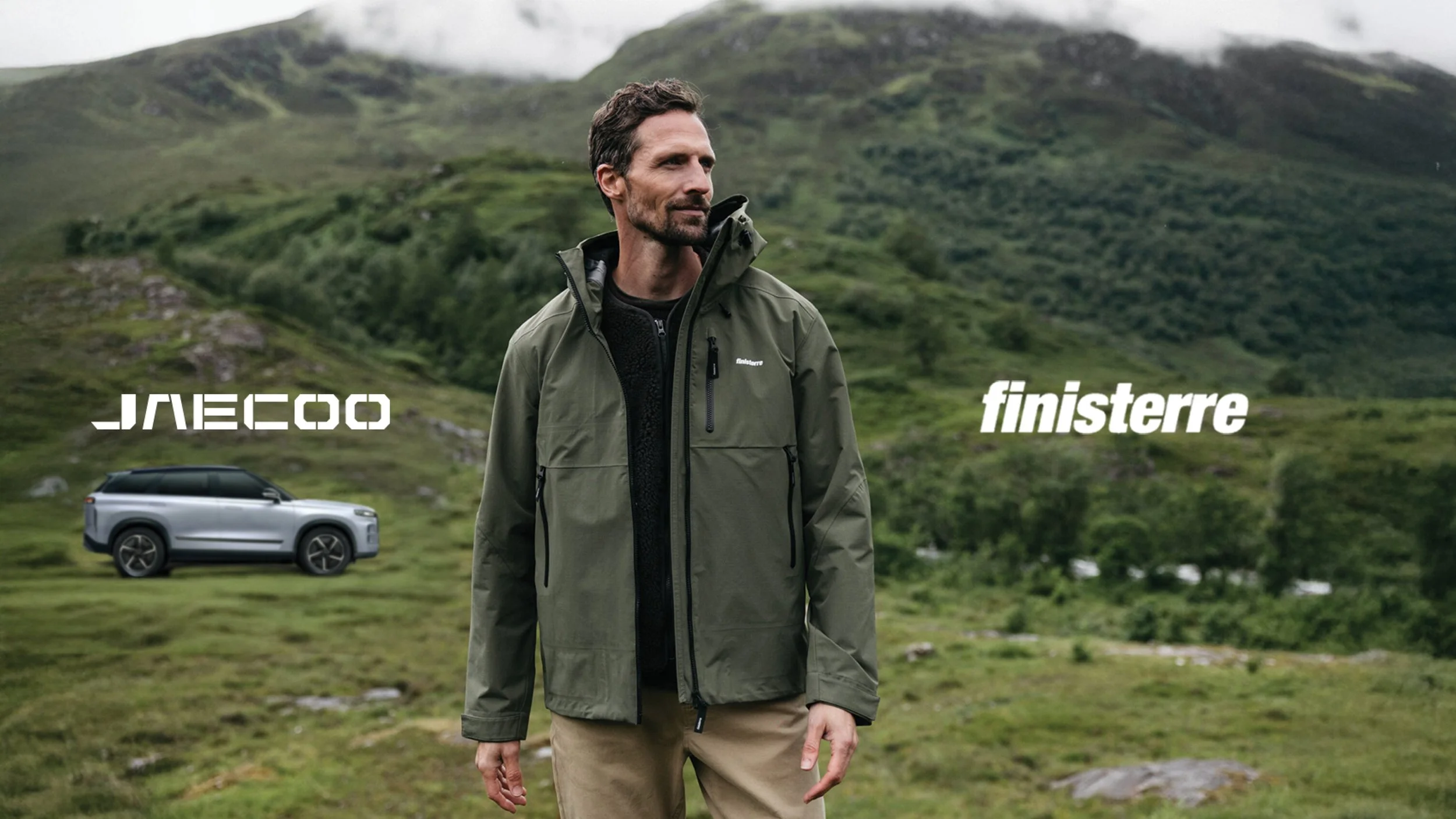 A man in an outdoor green jacket standing in a grassy, mountainous landscape with 'JAMECO' and 'finisterre' logos and a silver SUV in the background.